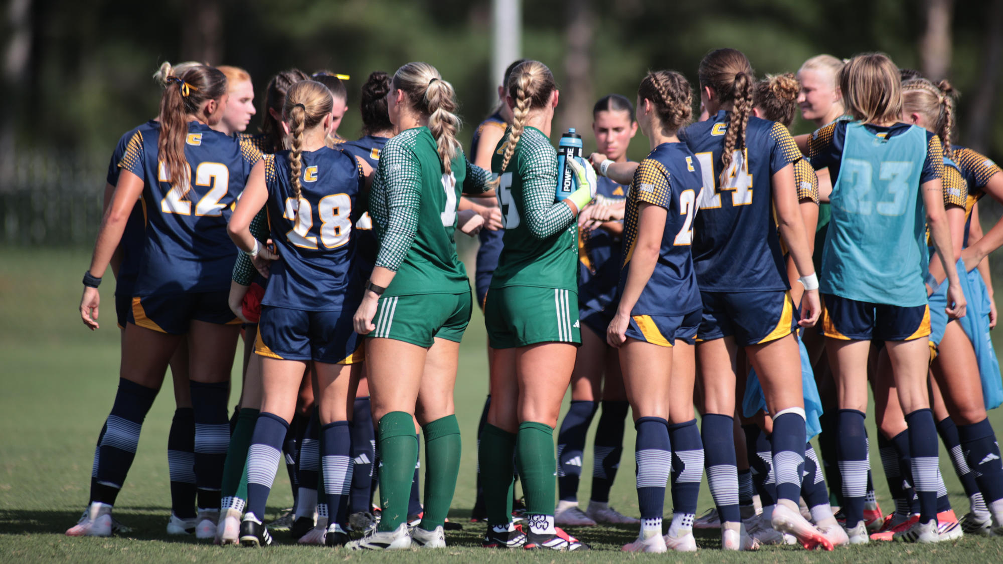 a group of soccer players are in a huddle before the game on the field.