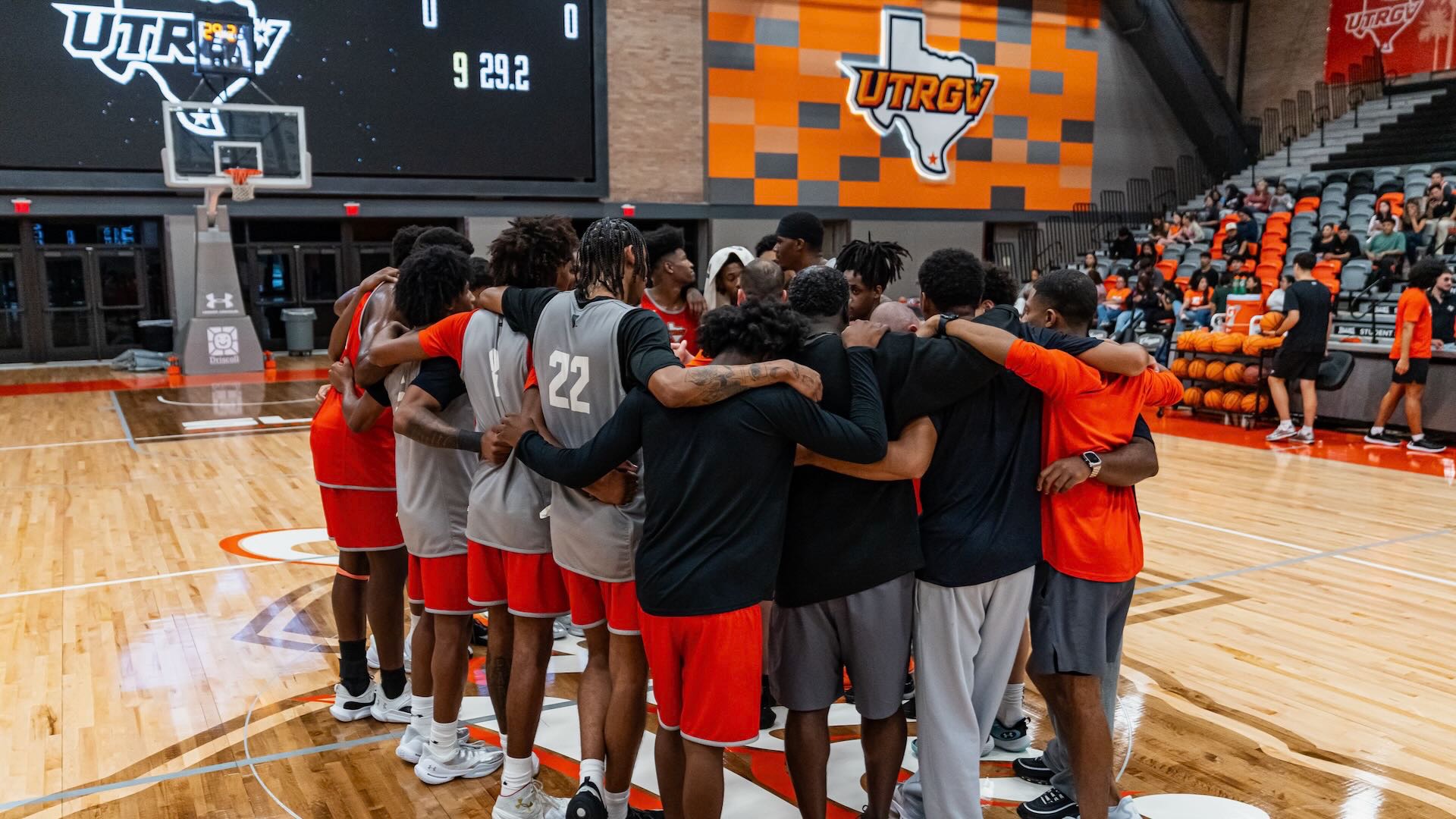 Image shows the utrgv men's basketball team huddled together during practice.