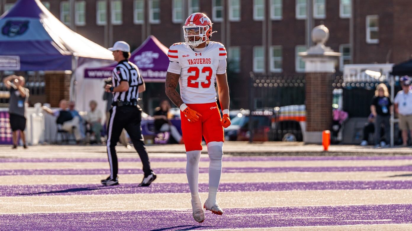 Jaiden Haygood stands on a football field wearing an orange helmet and pants and white uniform.