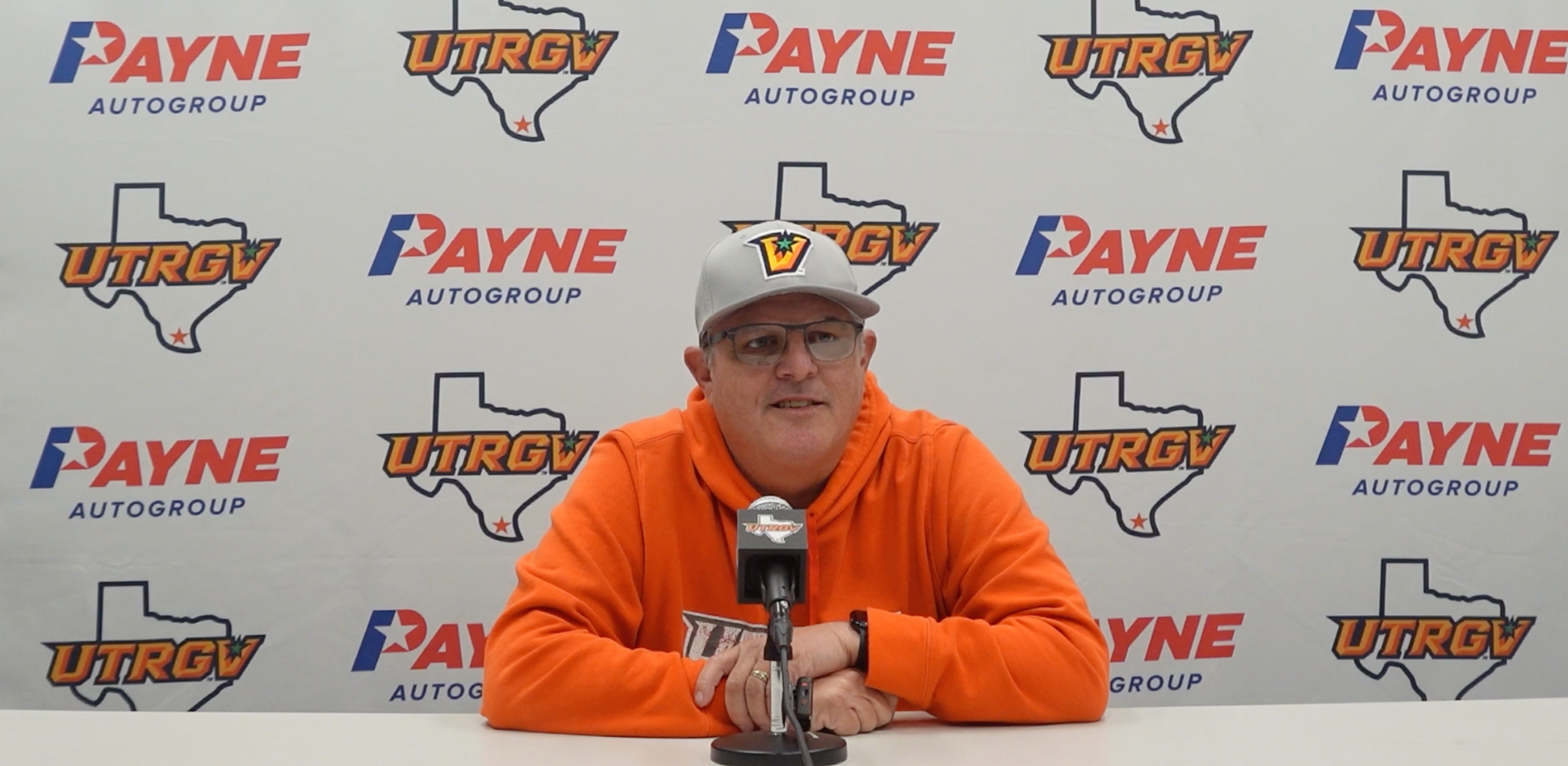Women's Basketball head coach Lane Lord in front of a Payne Auto Group and UTRGV branded backdrop at the weekly press conference