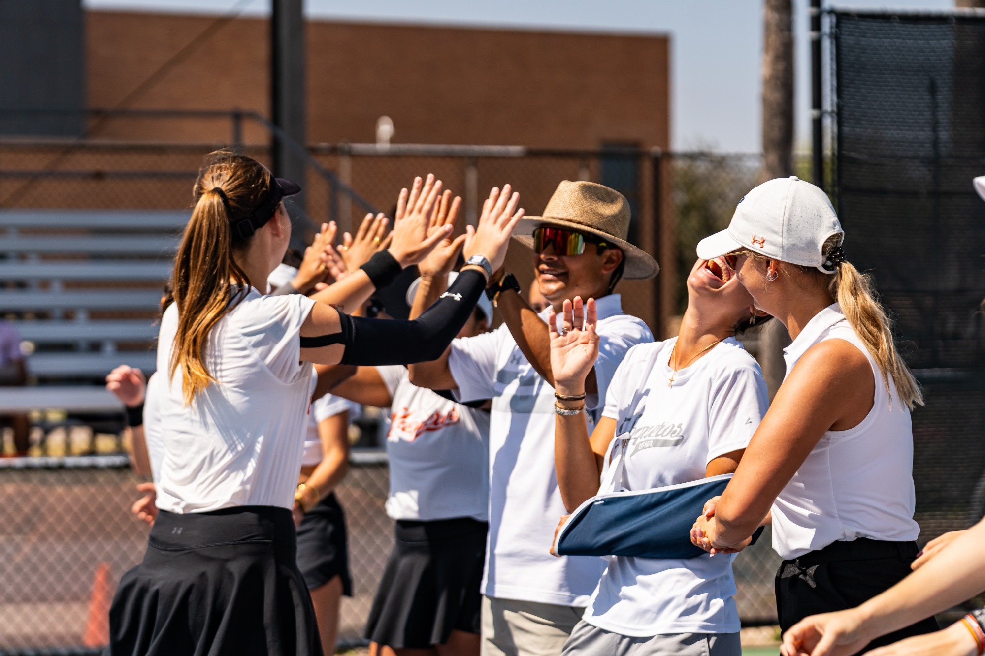 Photo of the Women's Tennis team high-fiving during doubles introductions