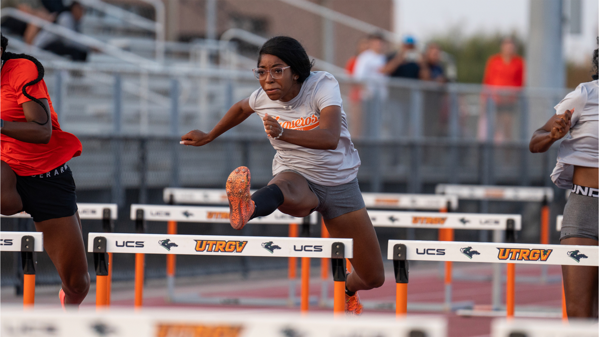 Image is a photo of UTRGV track & field freshman Dior Williams jumping over a hurdle during the Orange & Gray meet at the UTRGV Soccer and Track & Field Complex