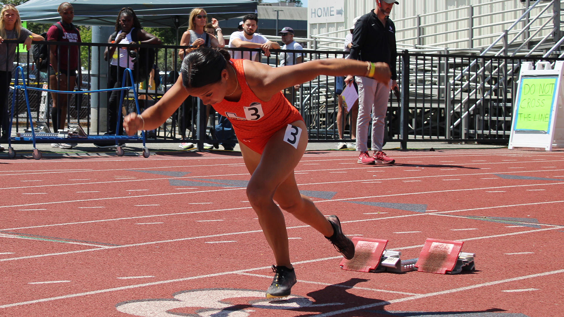 Image of Aliyah Castillo in an orange UTRGV track & field uniform coming out of the blocks on the track