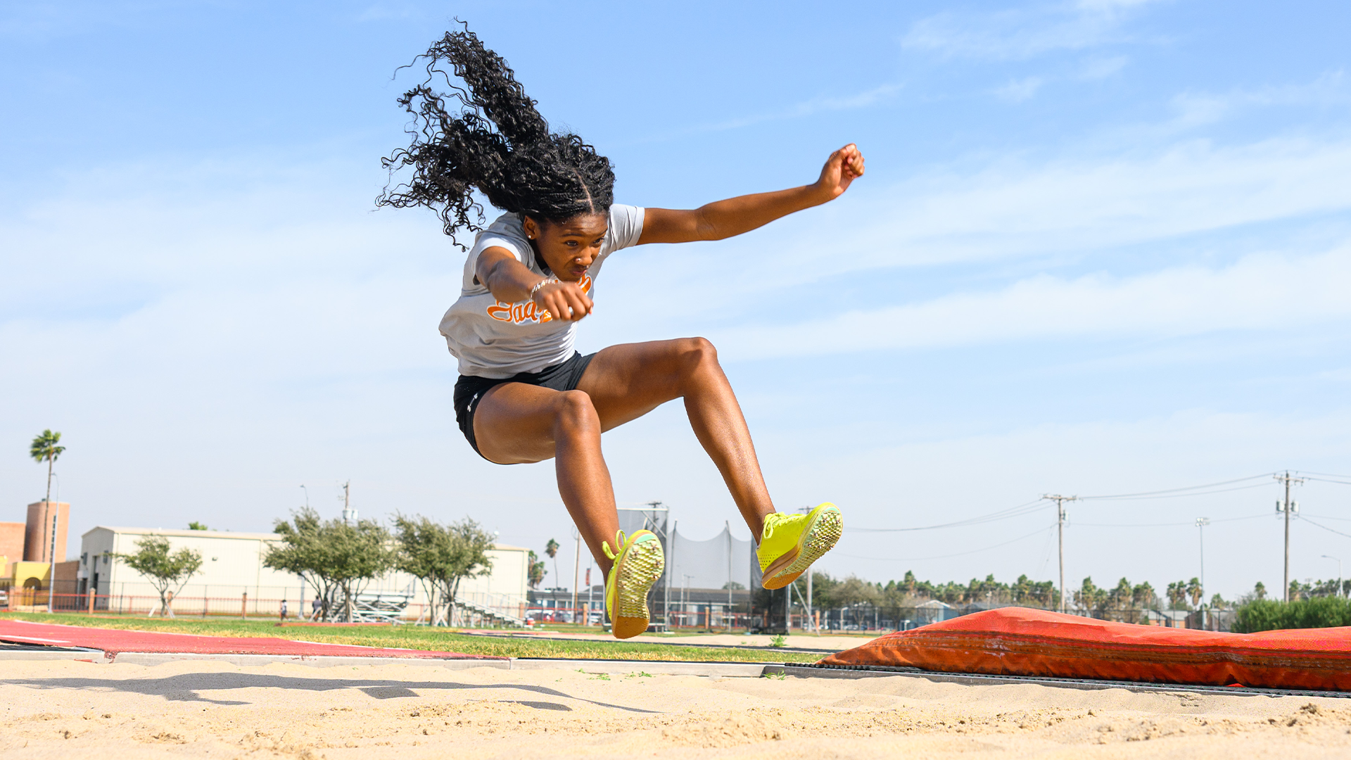 Photo of La'Zariah Bethany doing the triple jump in the air before landing in the jumps pit.