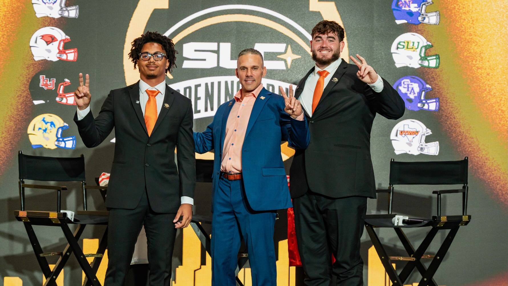 Image shows, from left to right, Jaiden Haygood, Travis Bush and Nick Hughes standing on stage holding their Vs up at the Southland Conference Opening Drive Football Media Day.