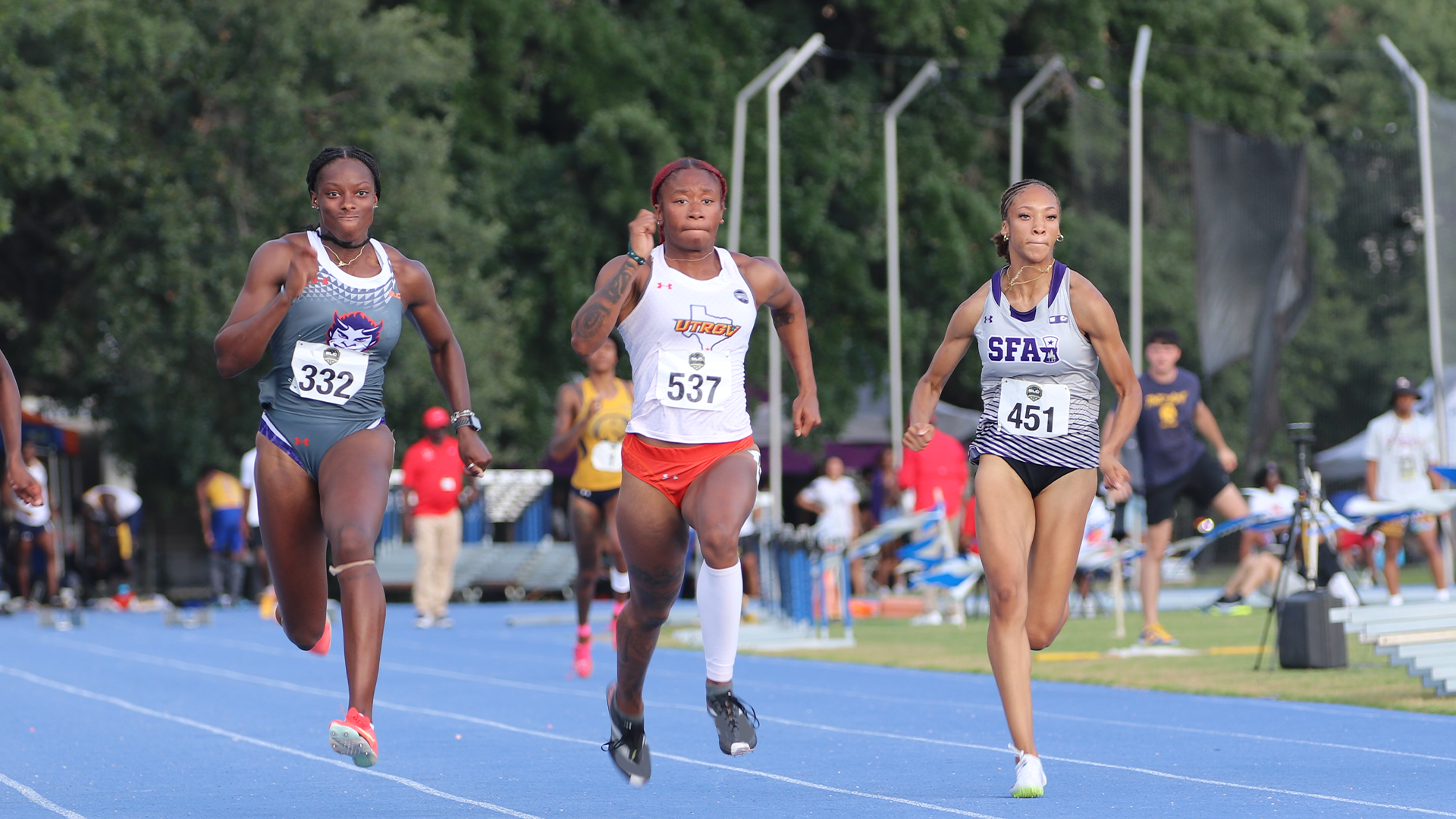 Image shows Nayla Harris in a white uniform top and orange bundies running the 100-meter dash.