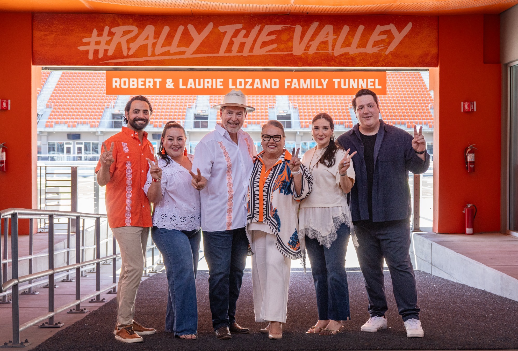 Photo of the Lozano Family putting their V's up under the Robert and Laurie Lozano Family Tunnel