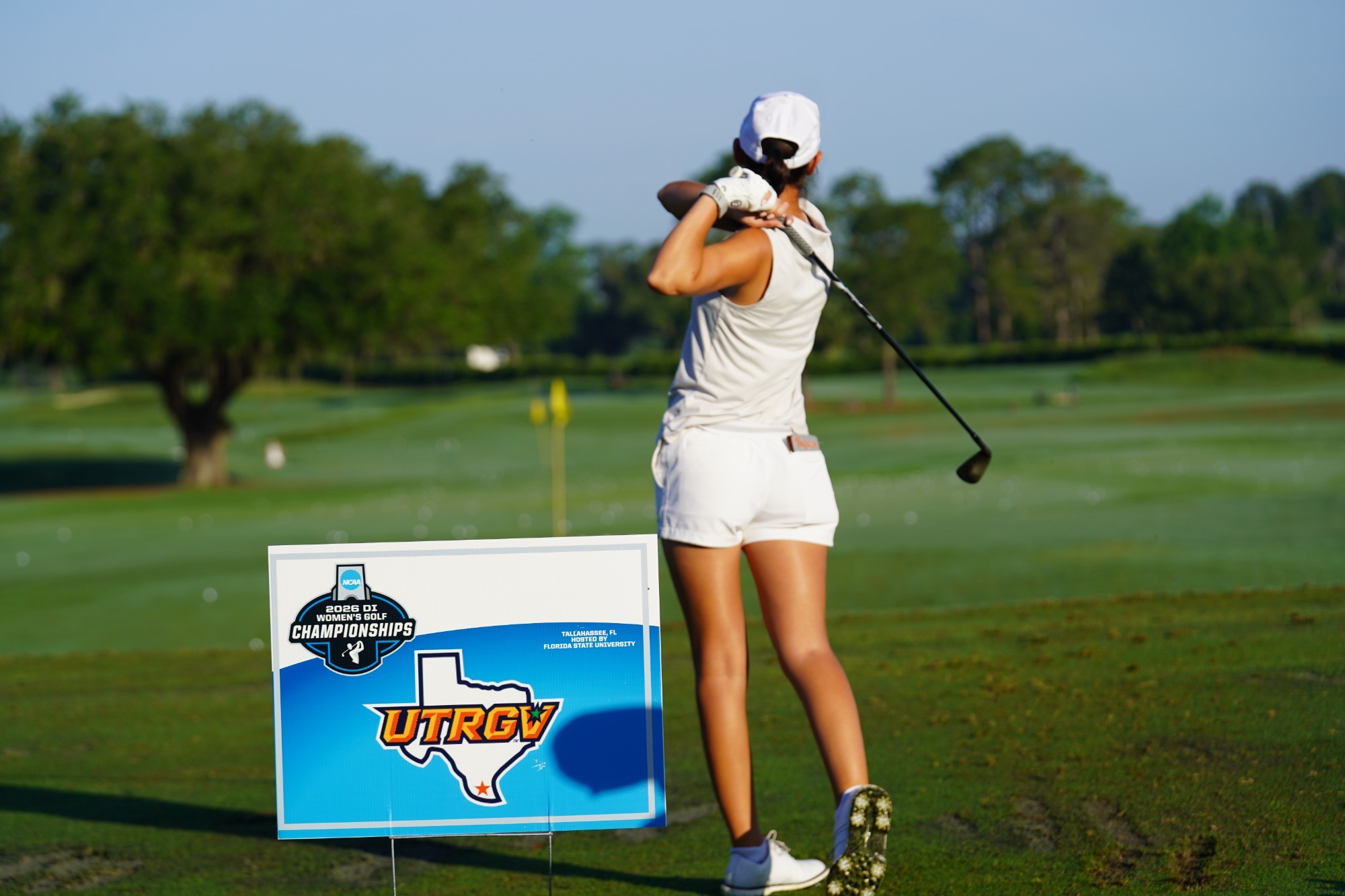 UTRGV Women's Golfer practicing beside sign at NCAA Tallahassee Regional with UTRGV logo