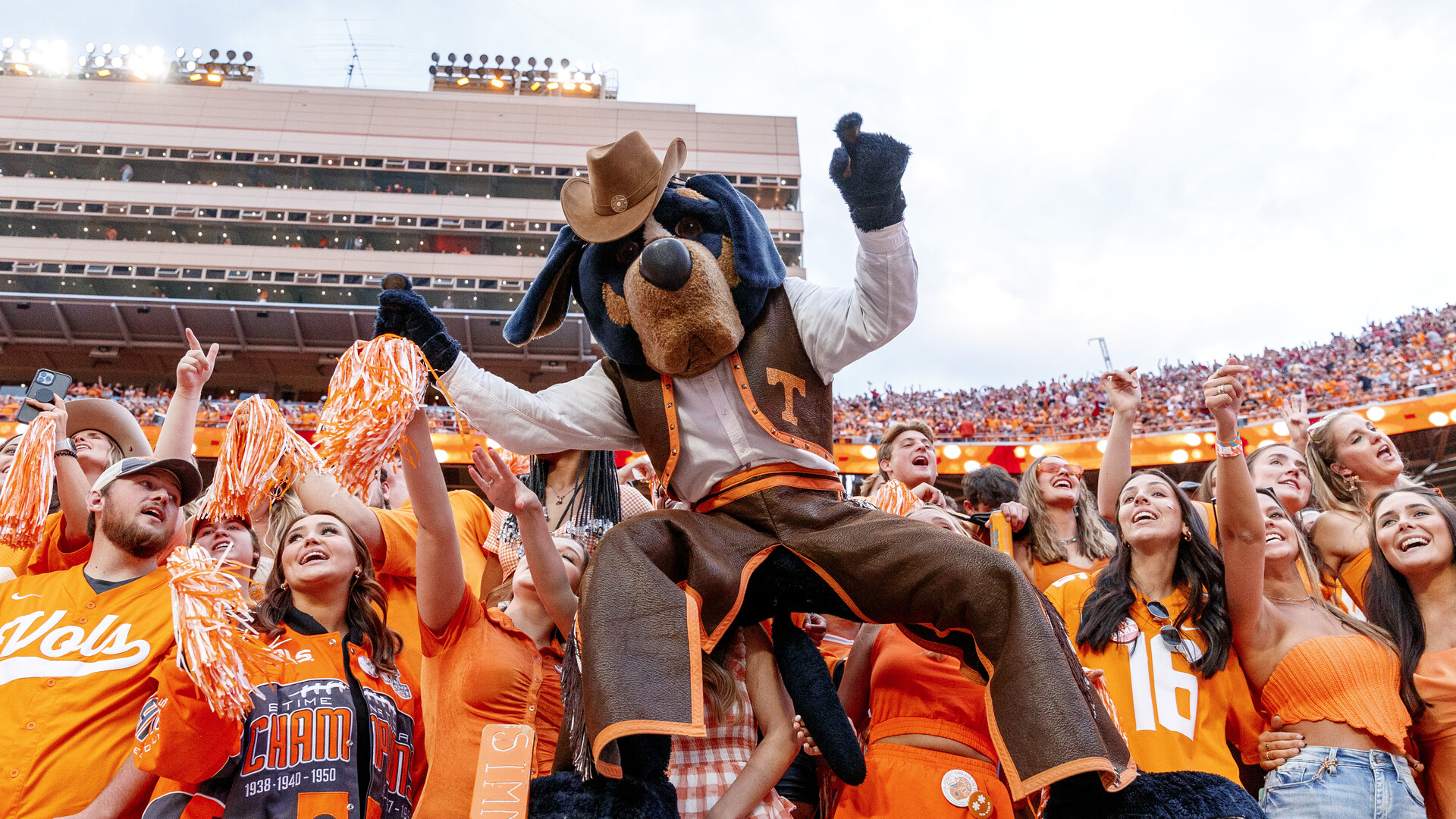 Tennessee's costumed Smokey mascot celebrating with orange-clad fans at Neyland Stadium