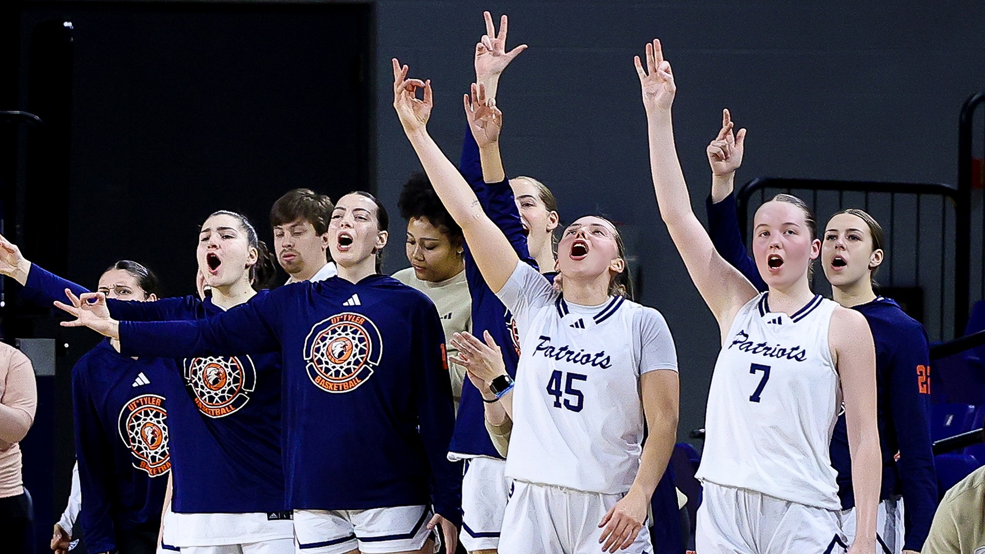 The Patriots bench celebrates a three pointer against Midwestern State