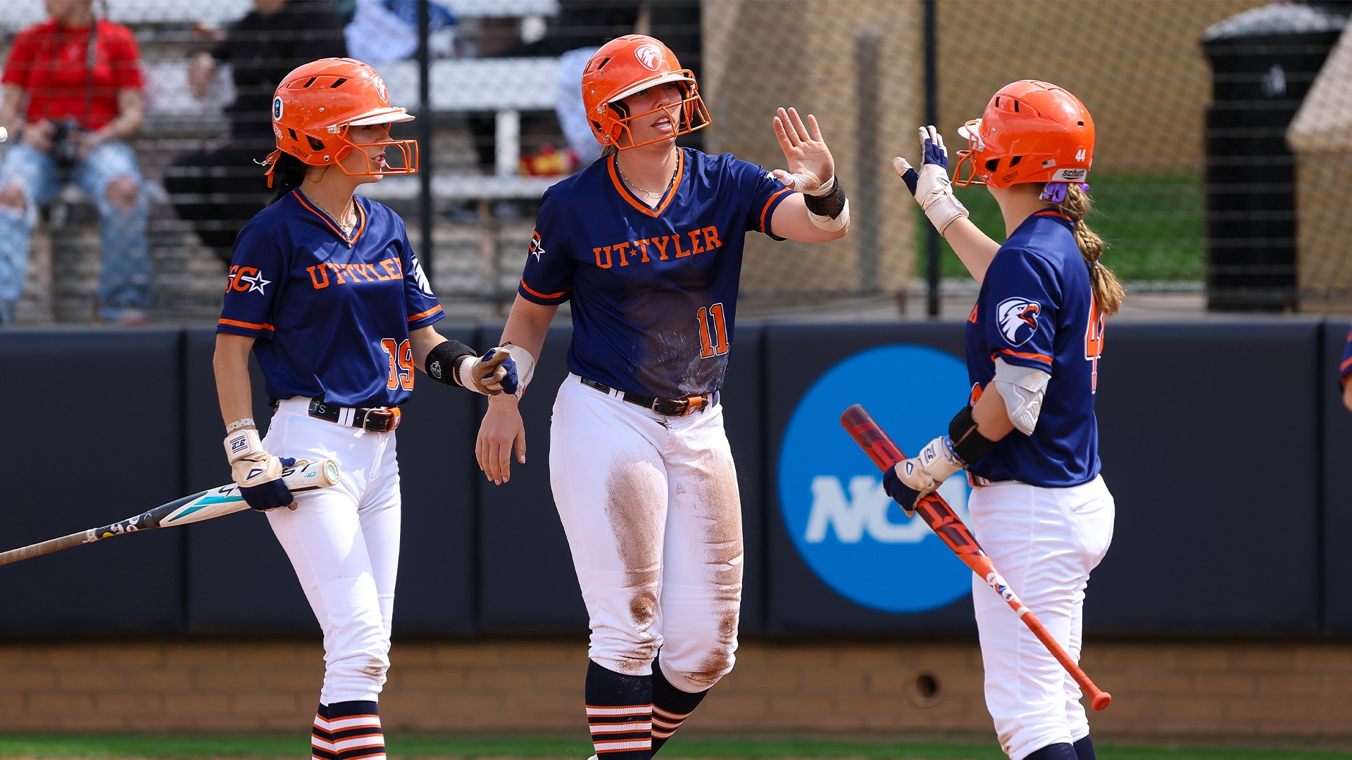 Dezirae Lopez, Taryn Barney, and Trinity Hale high five after a run against Sul Ross State