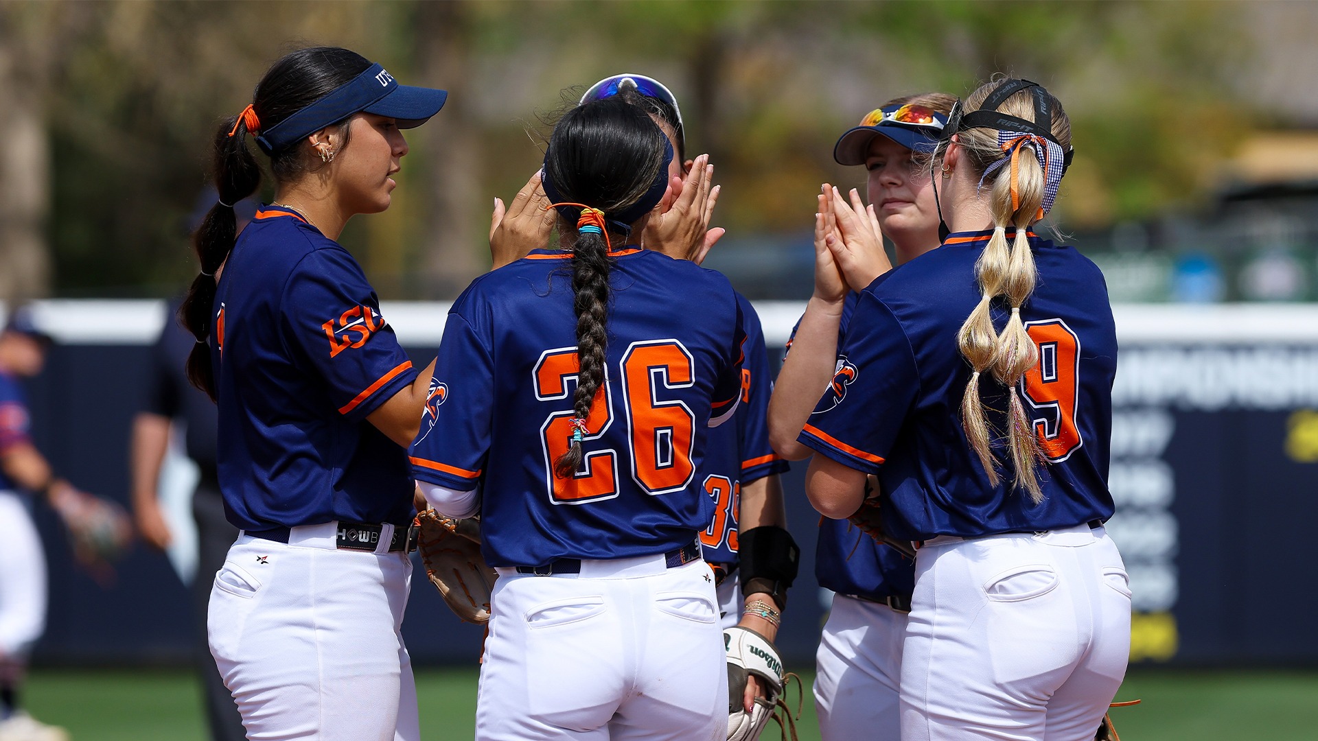 The Patriots infield high fives before starting an inning against Sul Ross State