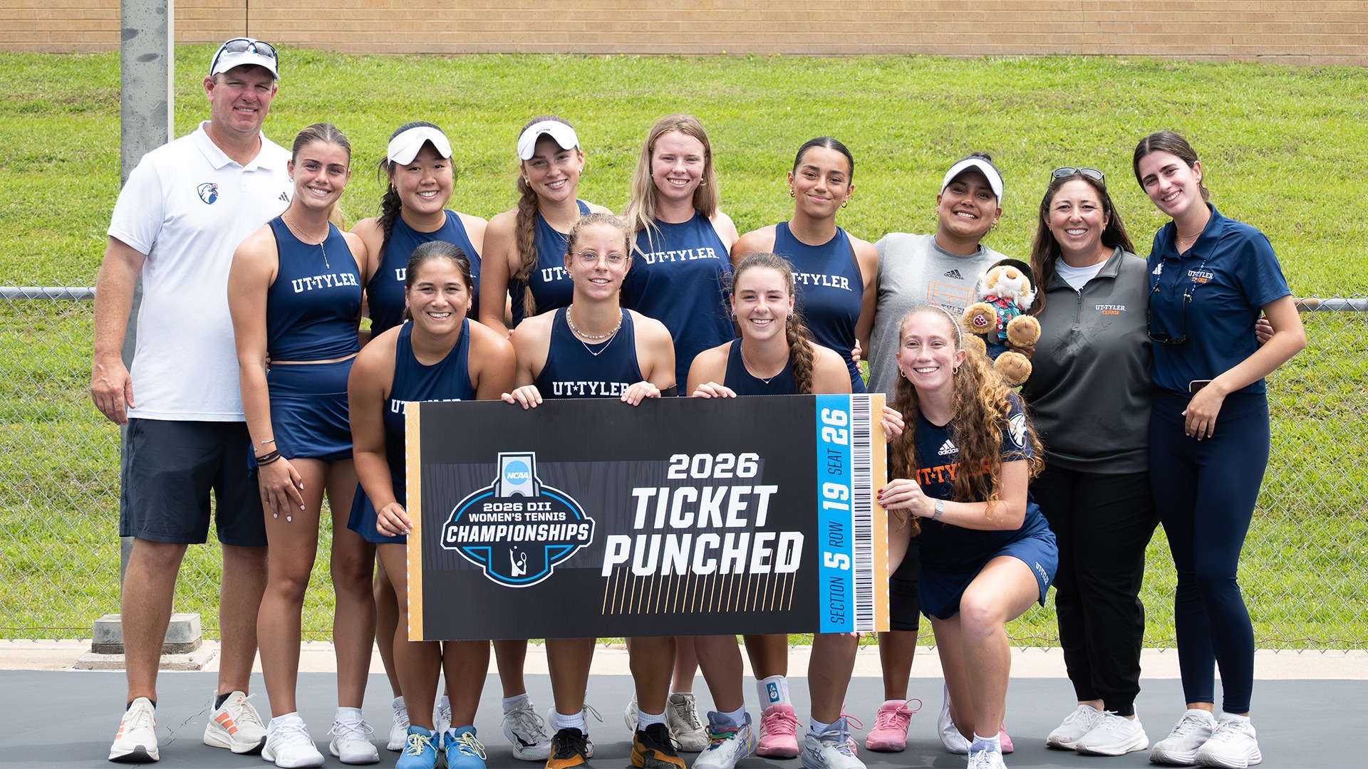 UT Tyler Women's Tennis stands with their ticket punched sign after defeating Lubbock Christian.