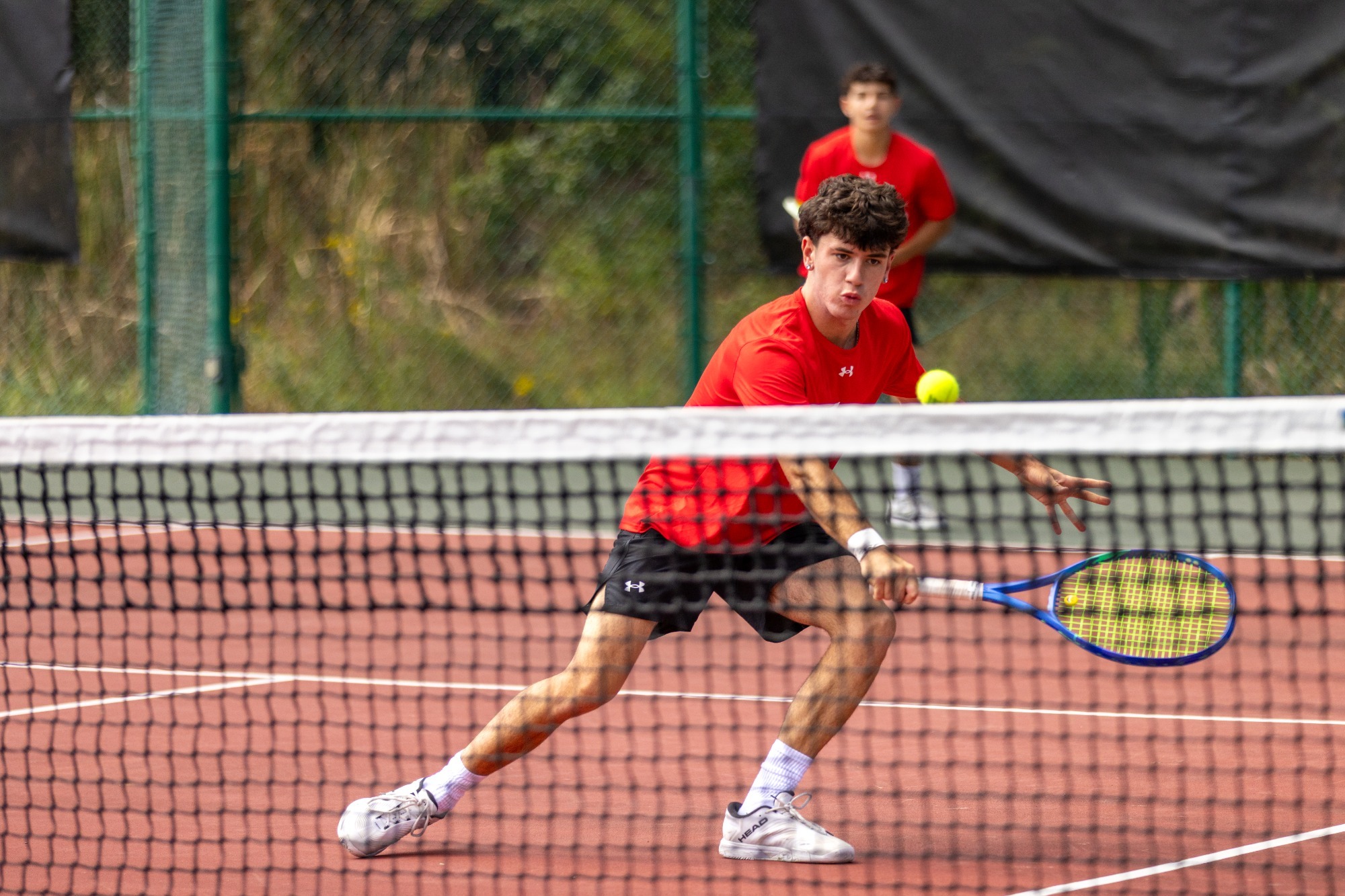 Men's Tennis player hits the ball vs Southern Virginia - 2025-26