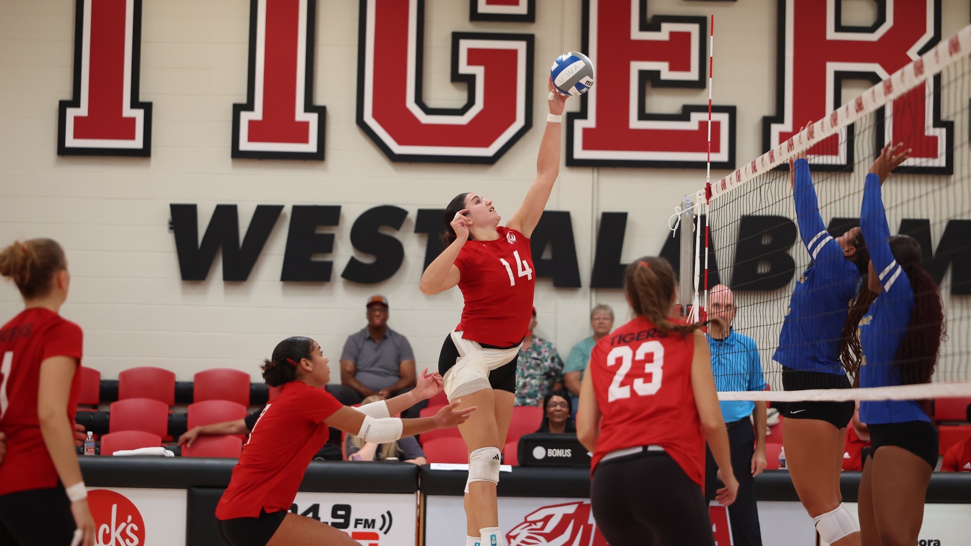 West Alabama's Katerina Korre (14) reaches high to attack the ball over two opposing blockers during a volleyball match inside Pruitt Hall.