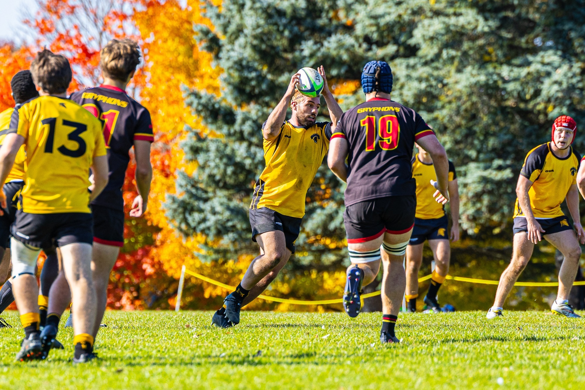 Men's Rugby Player catching the ball with a Guelph player running towards him