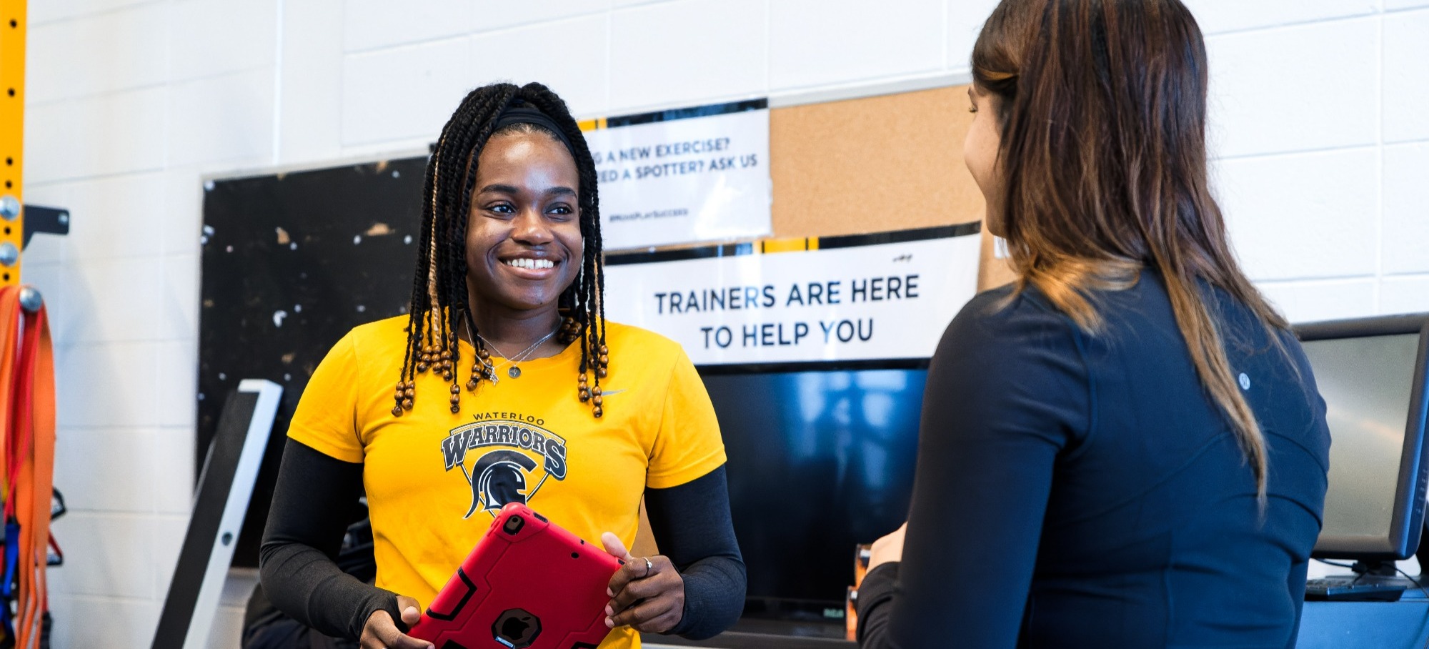 Fitness centre staff member holding ipad smiling at gym member
