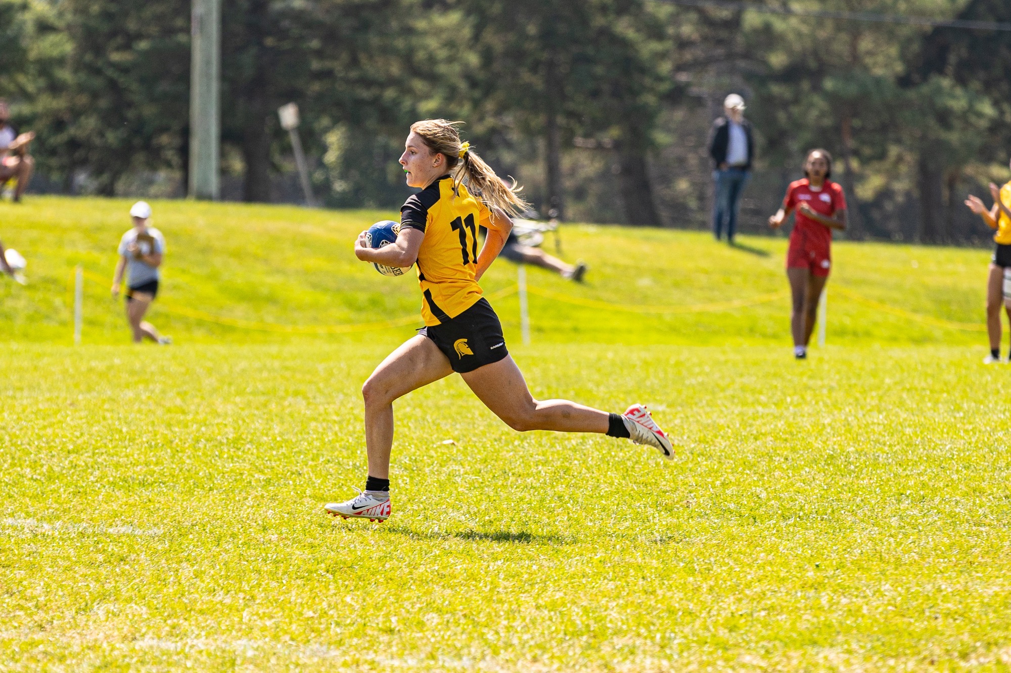 Waterloo Warriors women's rugby player running down the field with the ball