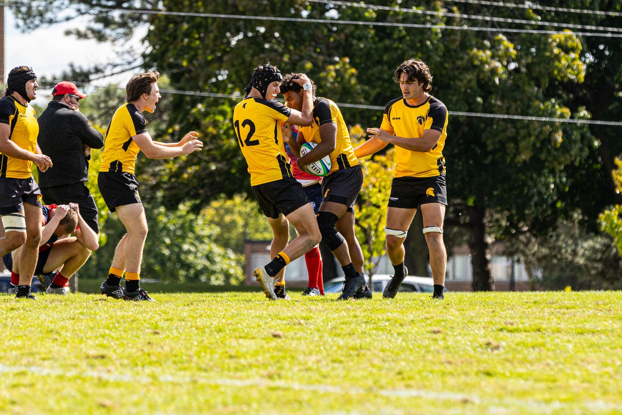 Warriors Men's Rugby player hugs his teammates with the ball in his hand