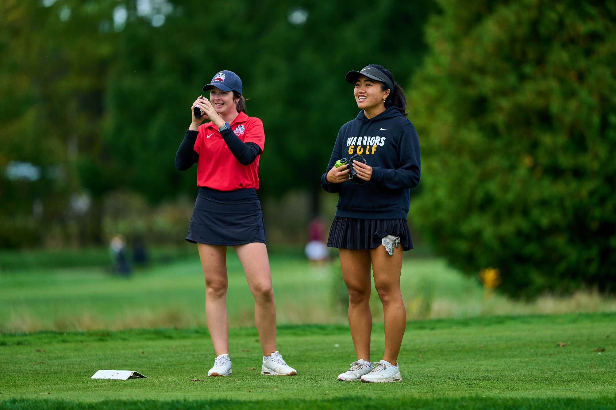 Two golfers look at the course from the green 