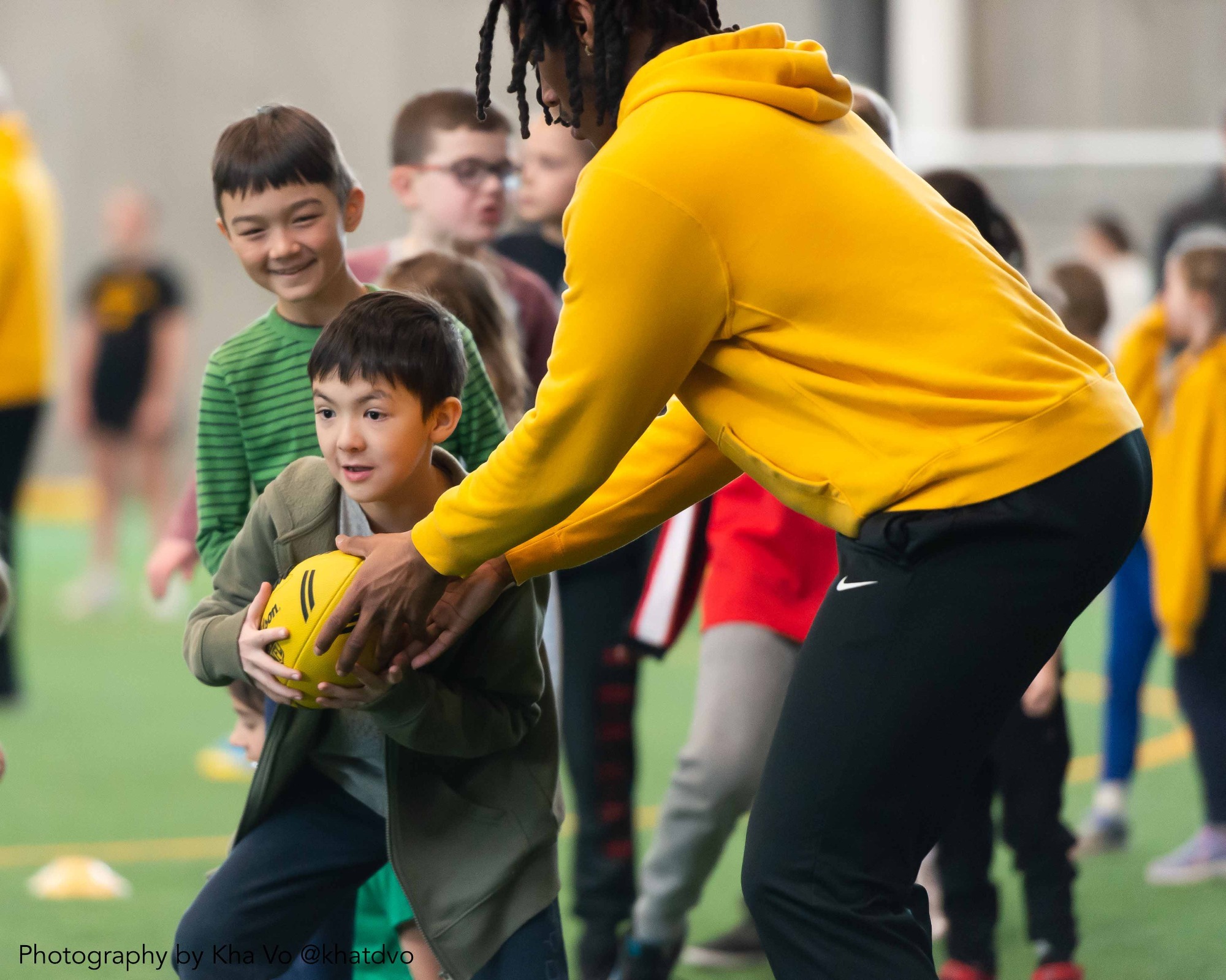 Warriors Family Day - young child running past a Warriors Football player with football