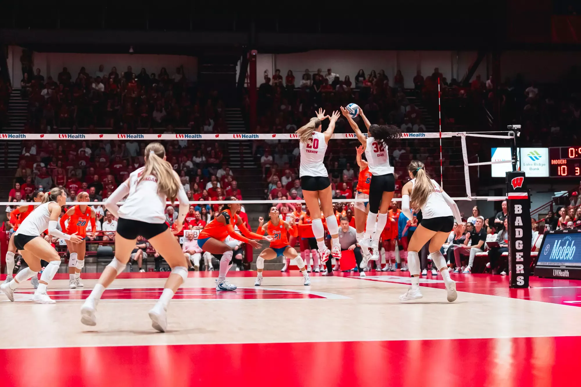 Wisconsin volleyball players jump to block an opponent’s attack at the net.