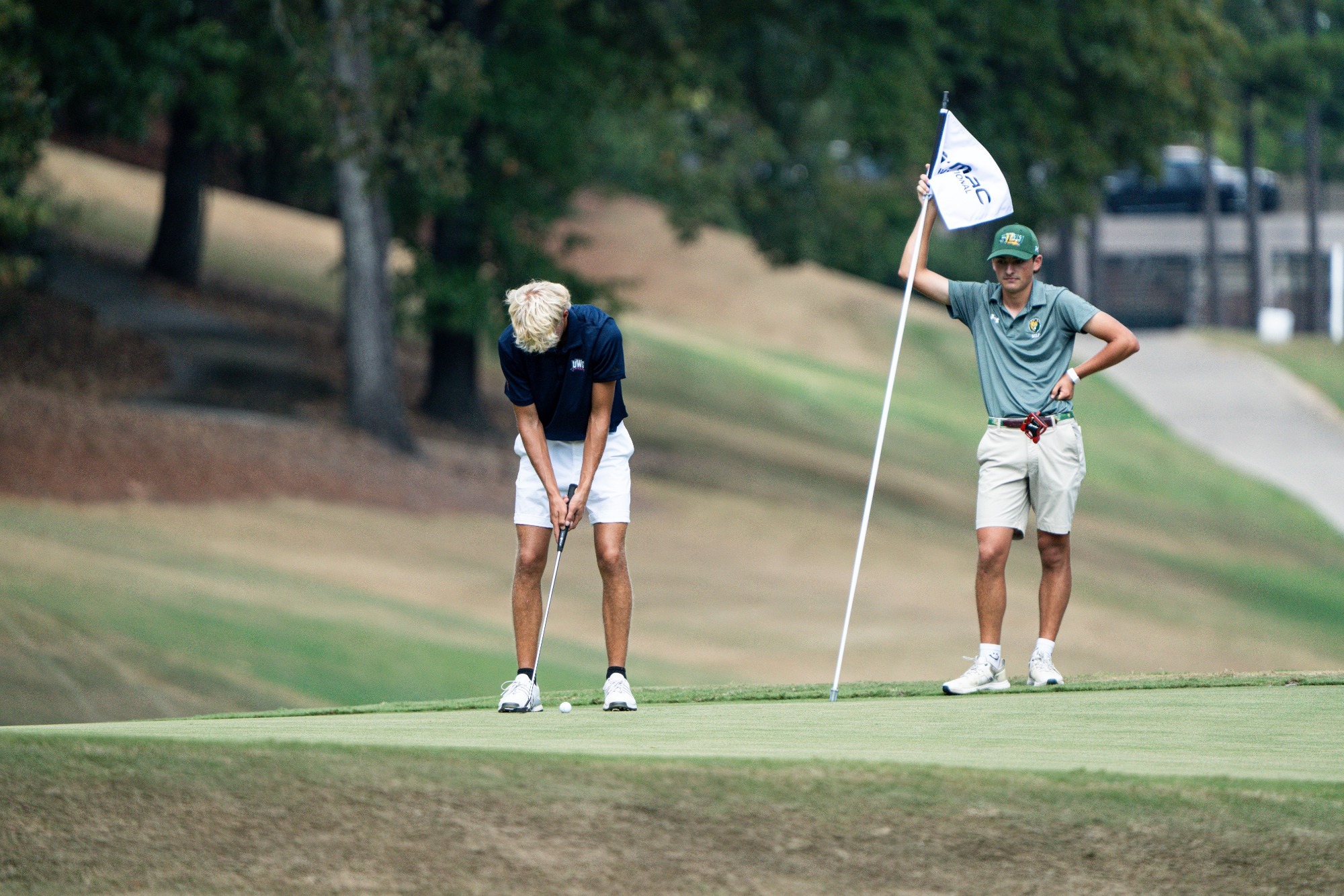 Dallas Inch, wearing a navy shirt and white short, putts in a collegiate golf tournament in Alabama.