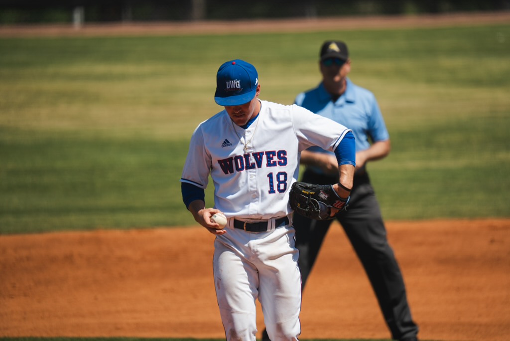 UWG baseball player in white looking at baseball