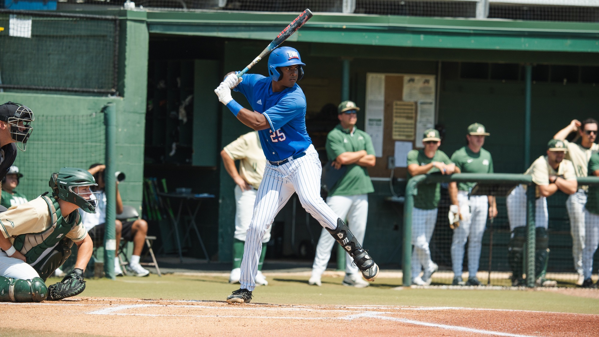 Player in blue jersey and helmet with white pants about to swing bat 