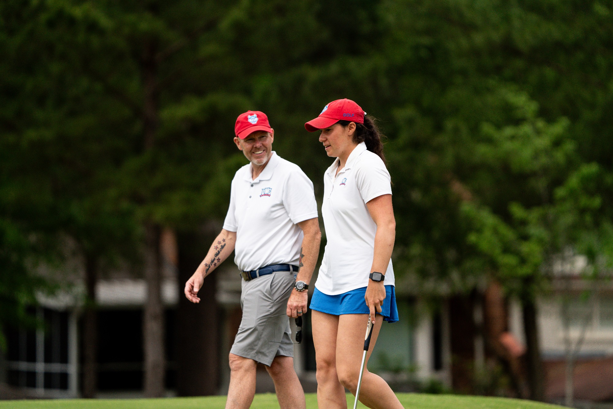 WGO ASUN Championship | Apr 17-19, 2026
UWG female golfer walks with head coach while wearing white shirt with blue shorts.
