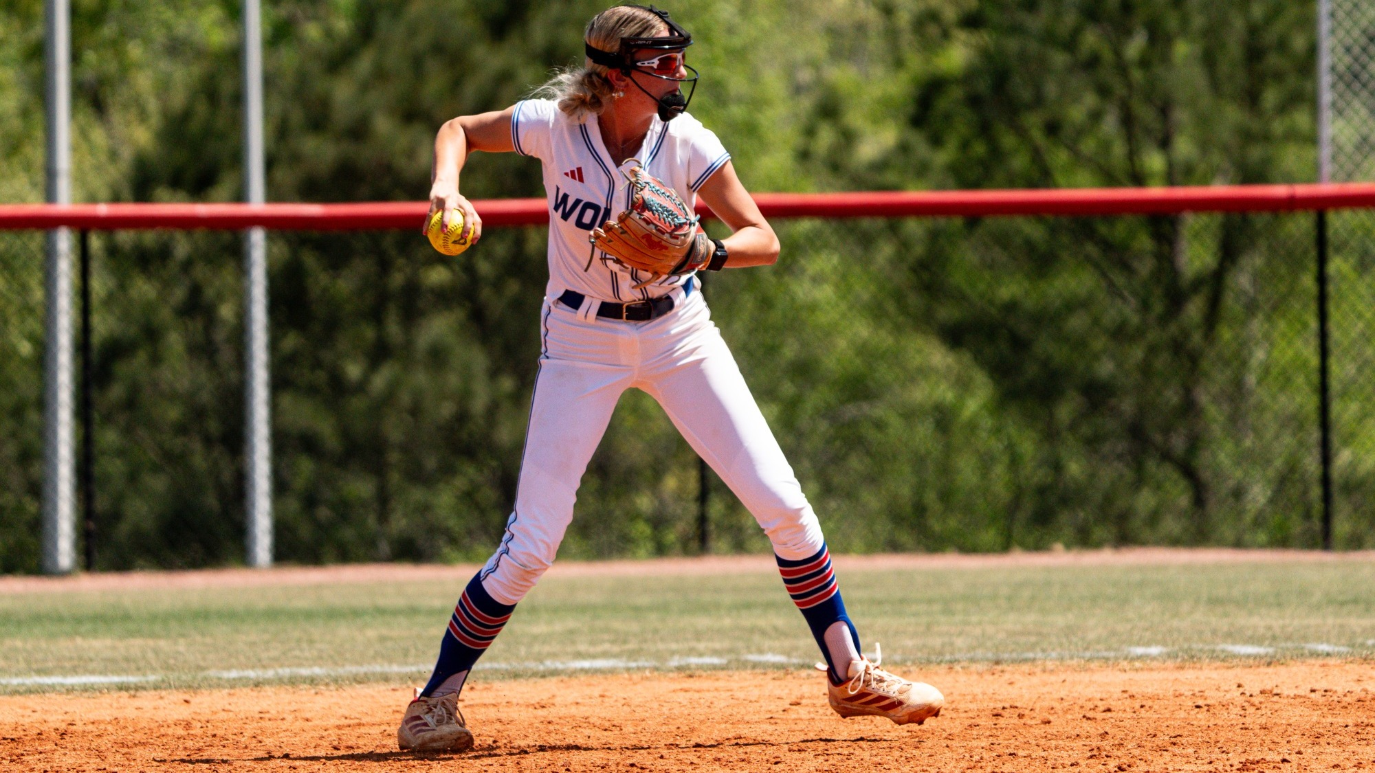 Dixiana Sims throws to first from her second base position during a UWG softball game. She is wearing UG's all white home uniform.