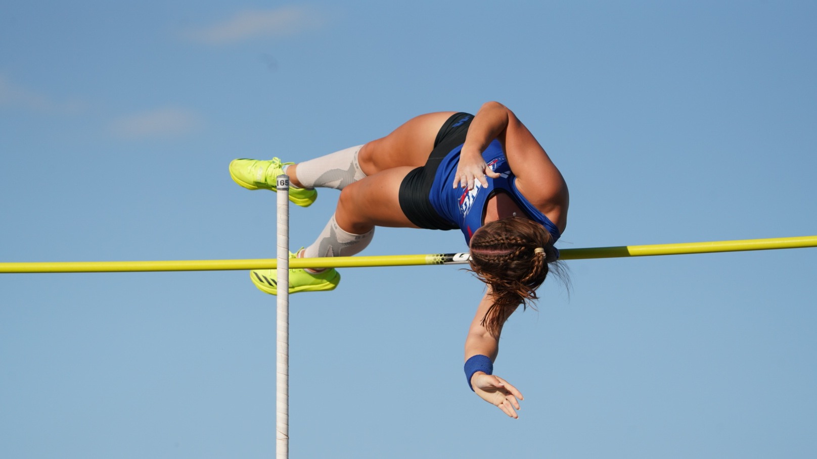 UWG’s Carleigh Bynum clears the bar during the pole vault competition at the ASUN Outdoor Championships in Jacksonville, Florida. Bynum is captured midair above the bar against a clear blue sky on her way to a first-place finish and gold medal performance.