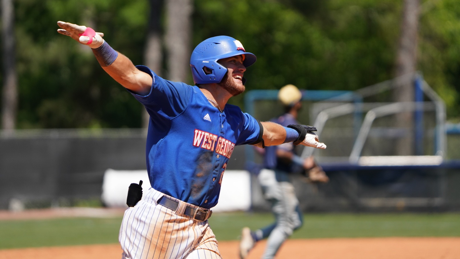 Player in blue jersey and hat with arms stretch while he is smiling 