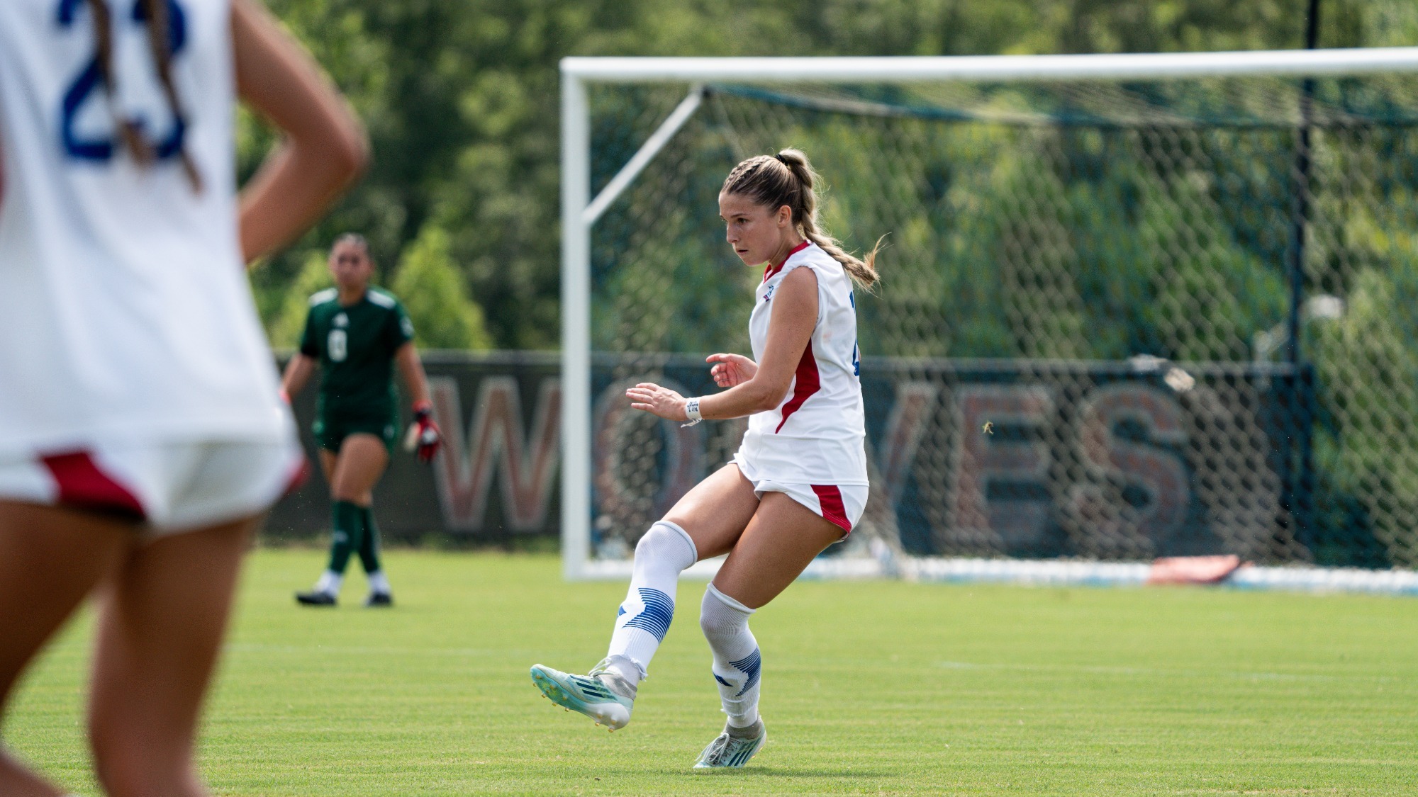 Taylor Richardson kicking a ball with Emily Sanabria standing in the back. 
