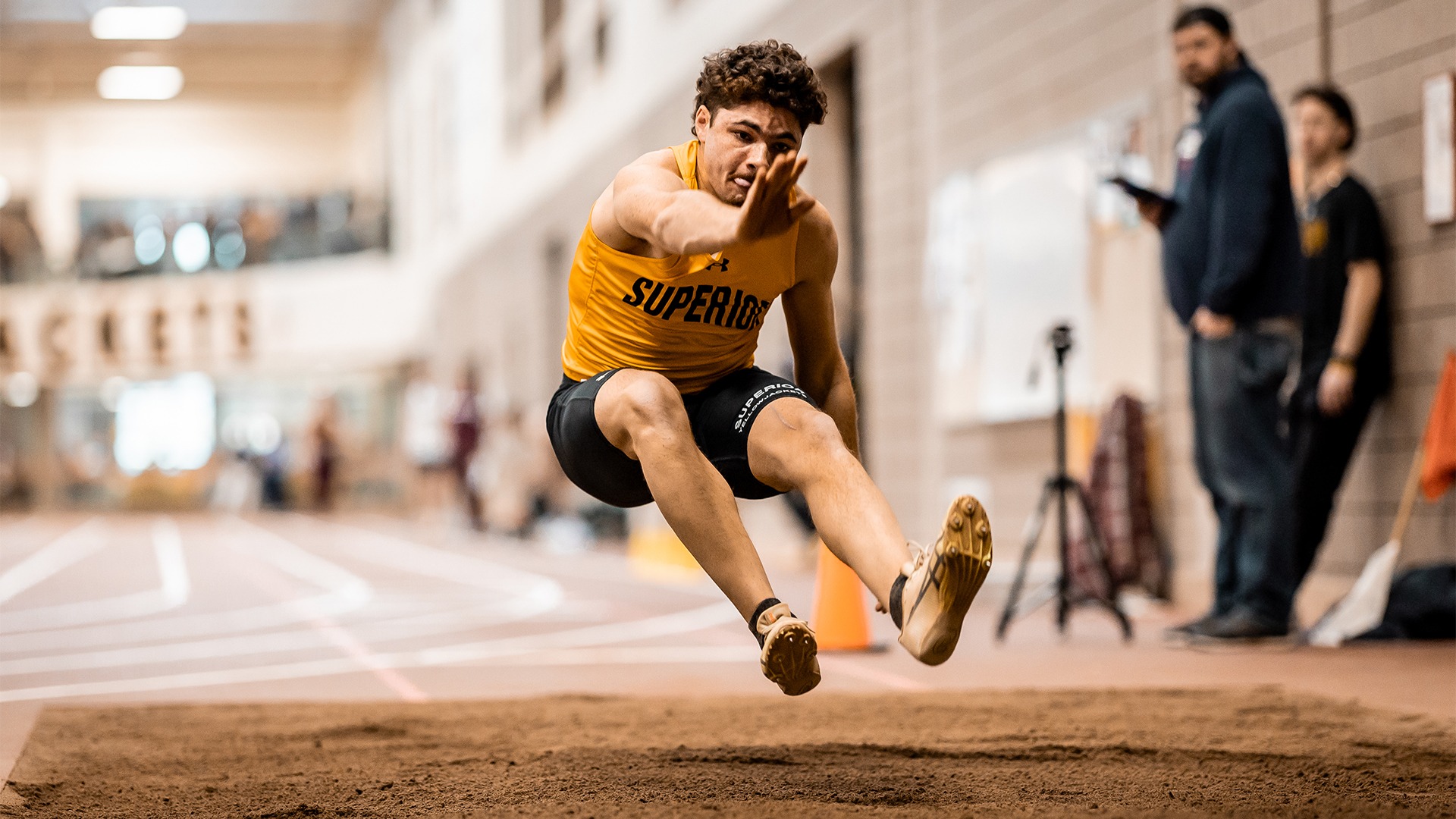 Sawyer Ferdon mid-jump at the long jump pit.