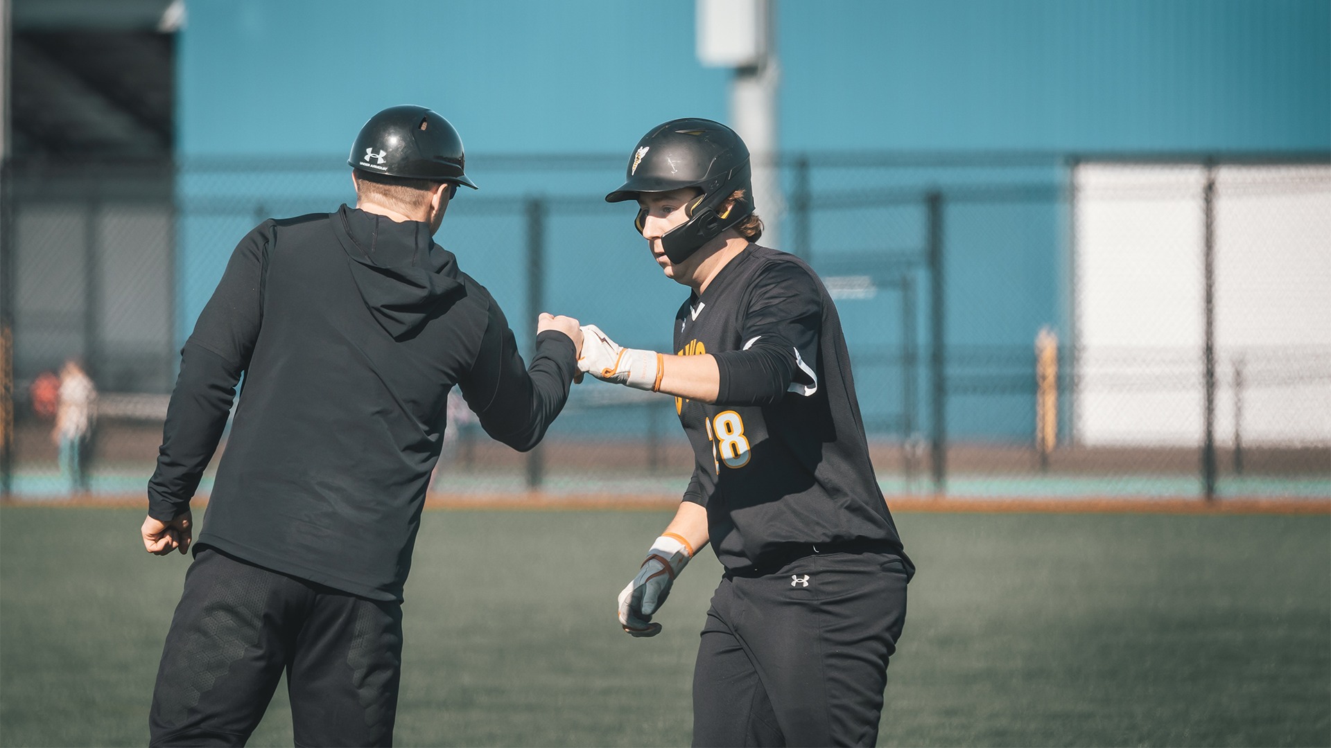 Trey Sybrant fist-bumping assistant coach Shaun Marshall at first base.