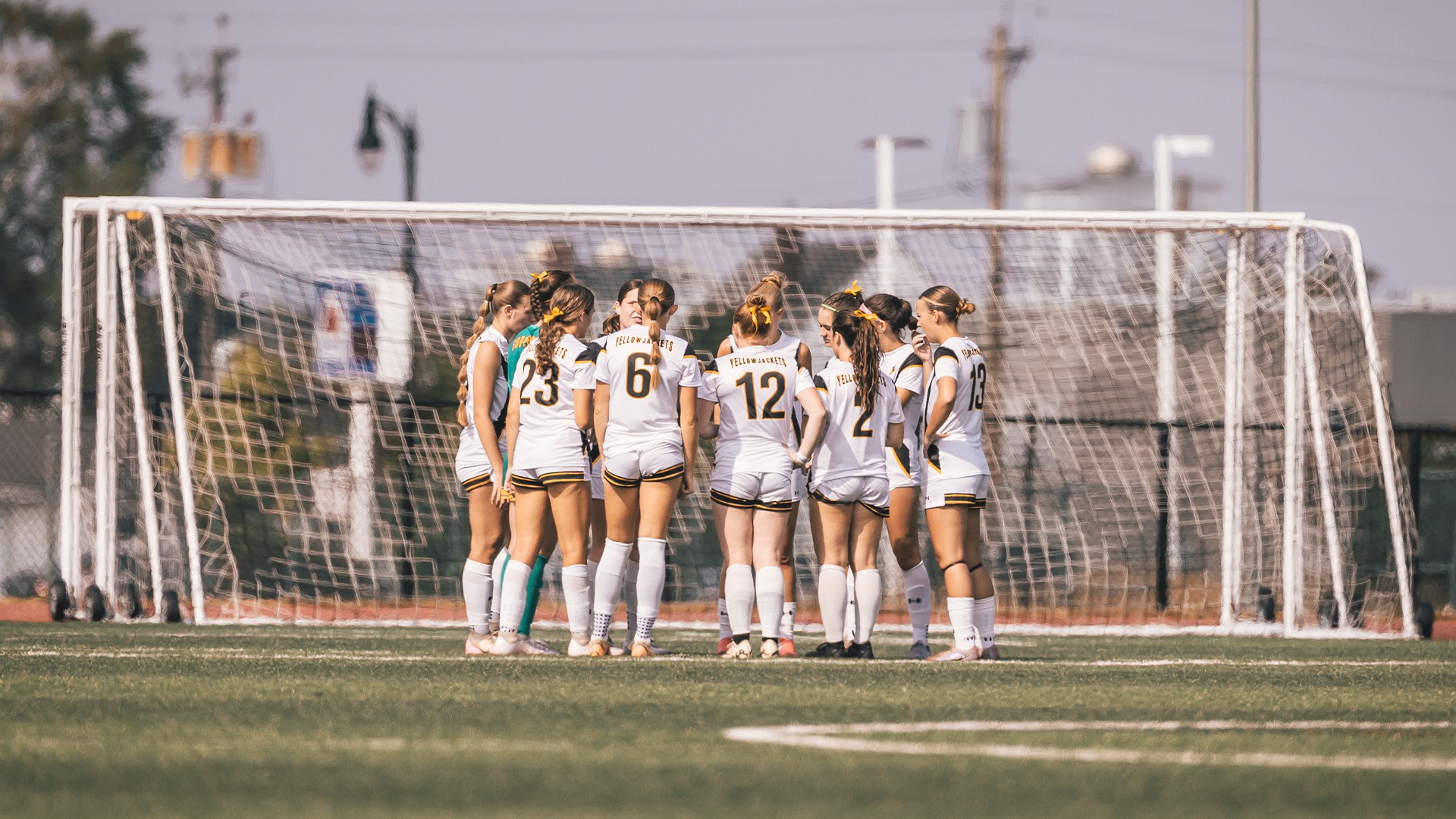 A team huddle with players of the women's soccer team on the field.