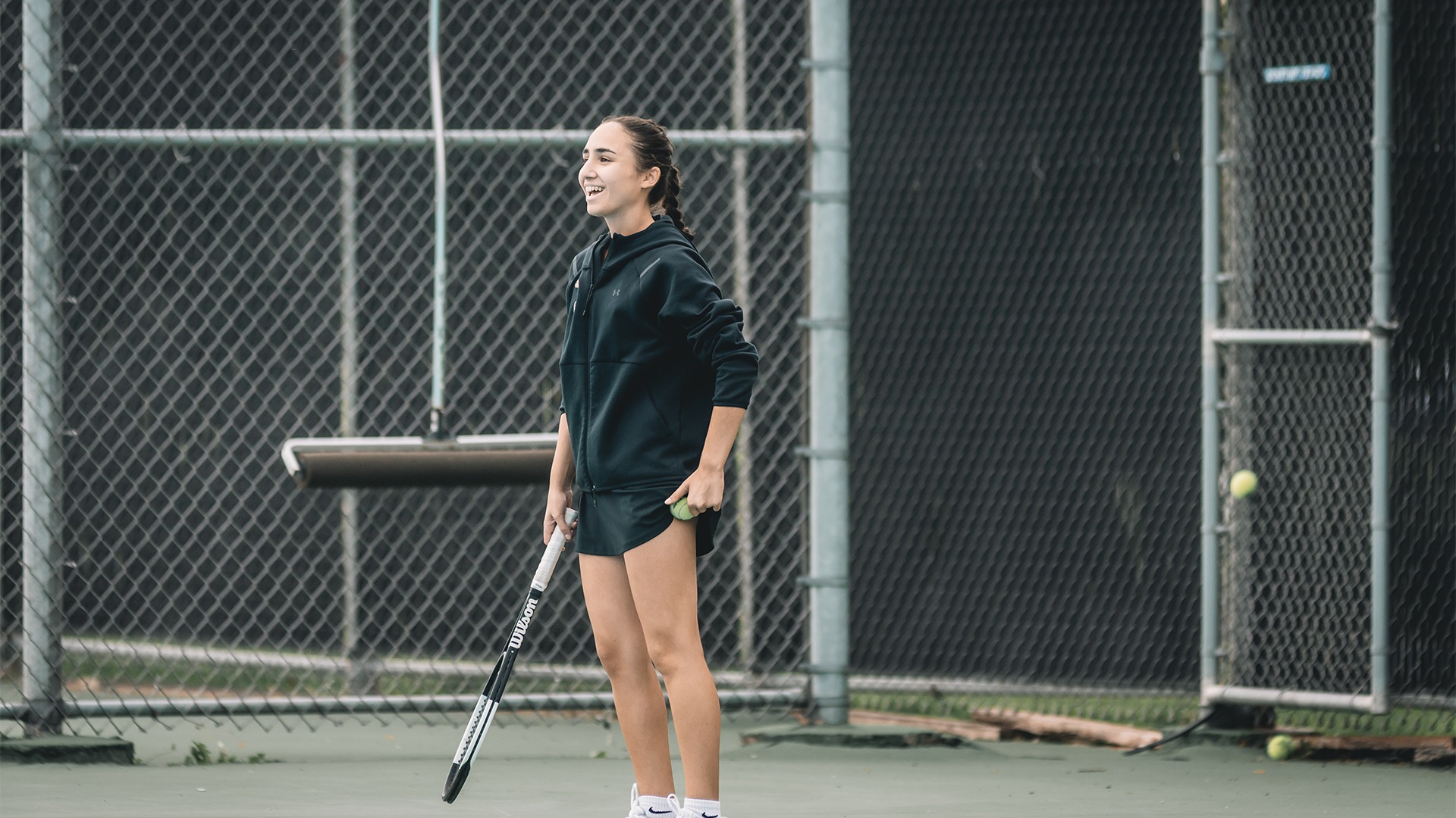 Elif Oezen smiling on the tennis courts holding a tennis ball.
