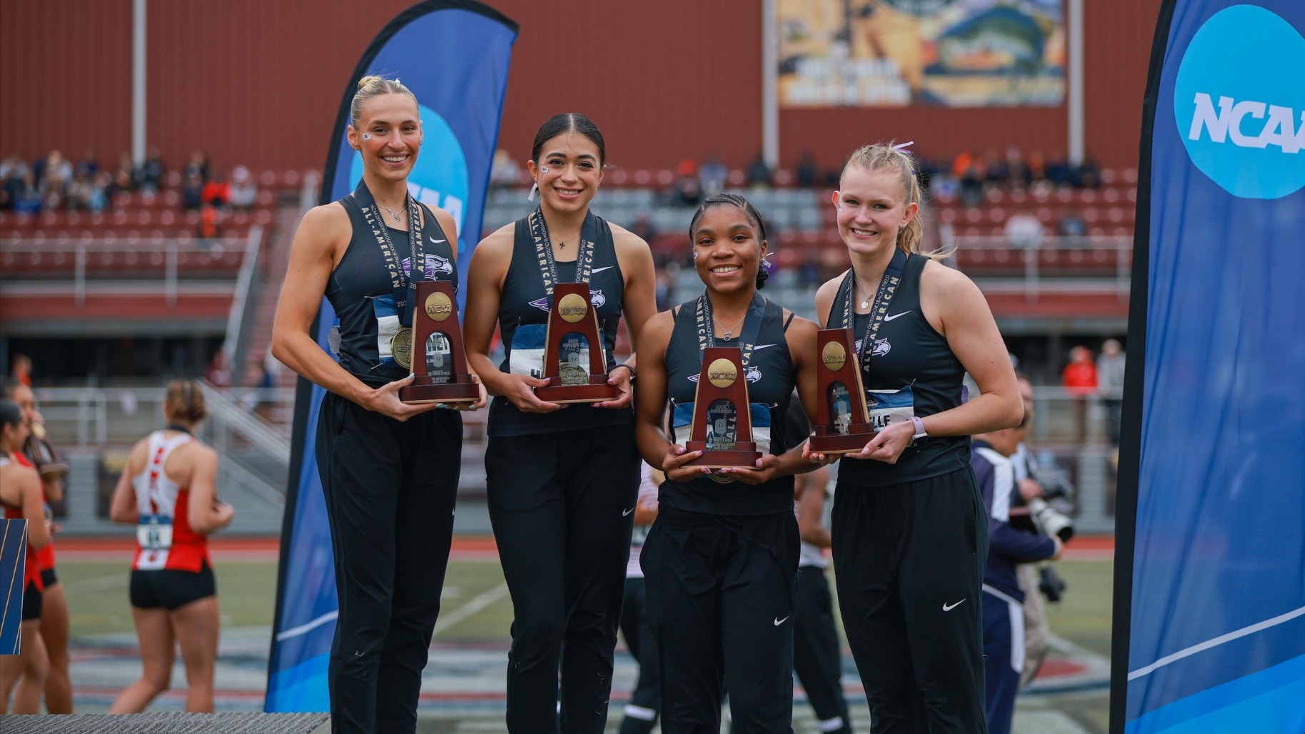 Women's 4x100 poses with trophies