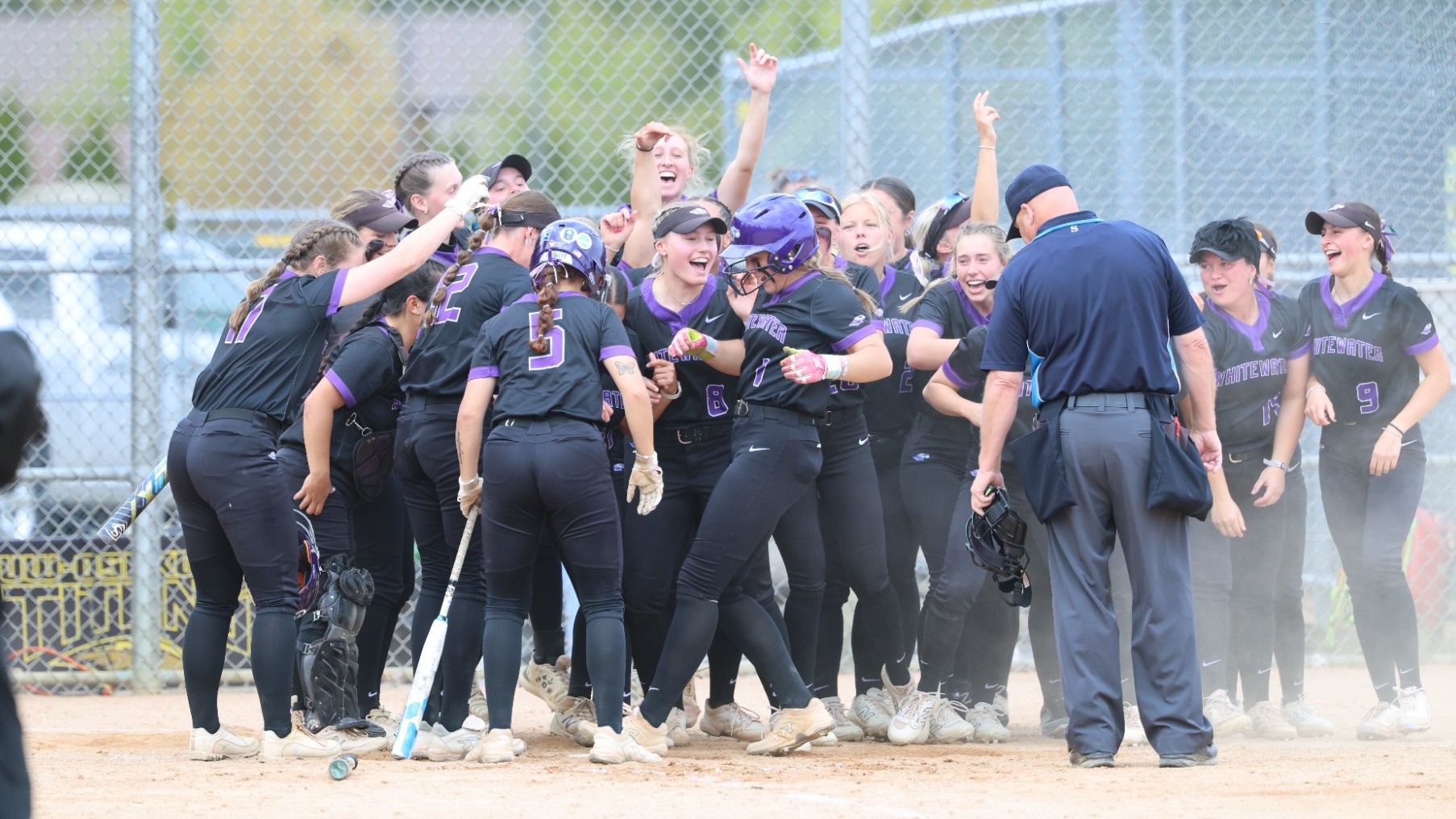 Grace Grabowy touches home while her teammates celebrate after hitting a homerun in a WIAC Quarterfinal