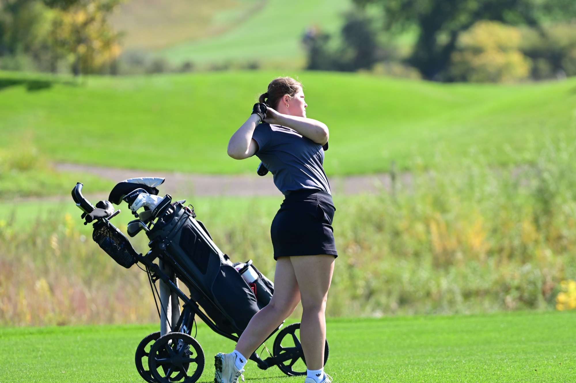 Pre-tournament story pic- Frontier Conference Meet 2026, Sadie Neustel in her backswing after placing a ball on the green.