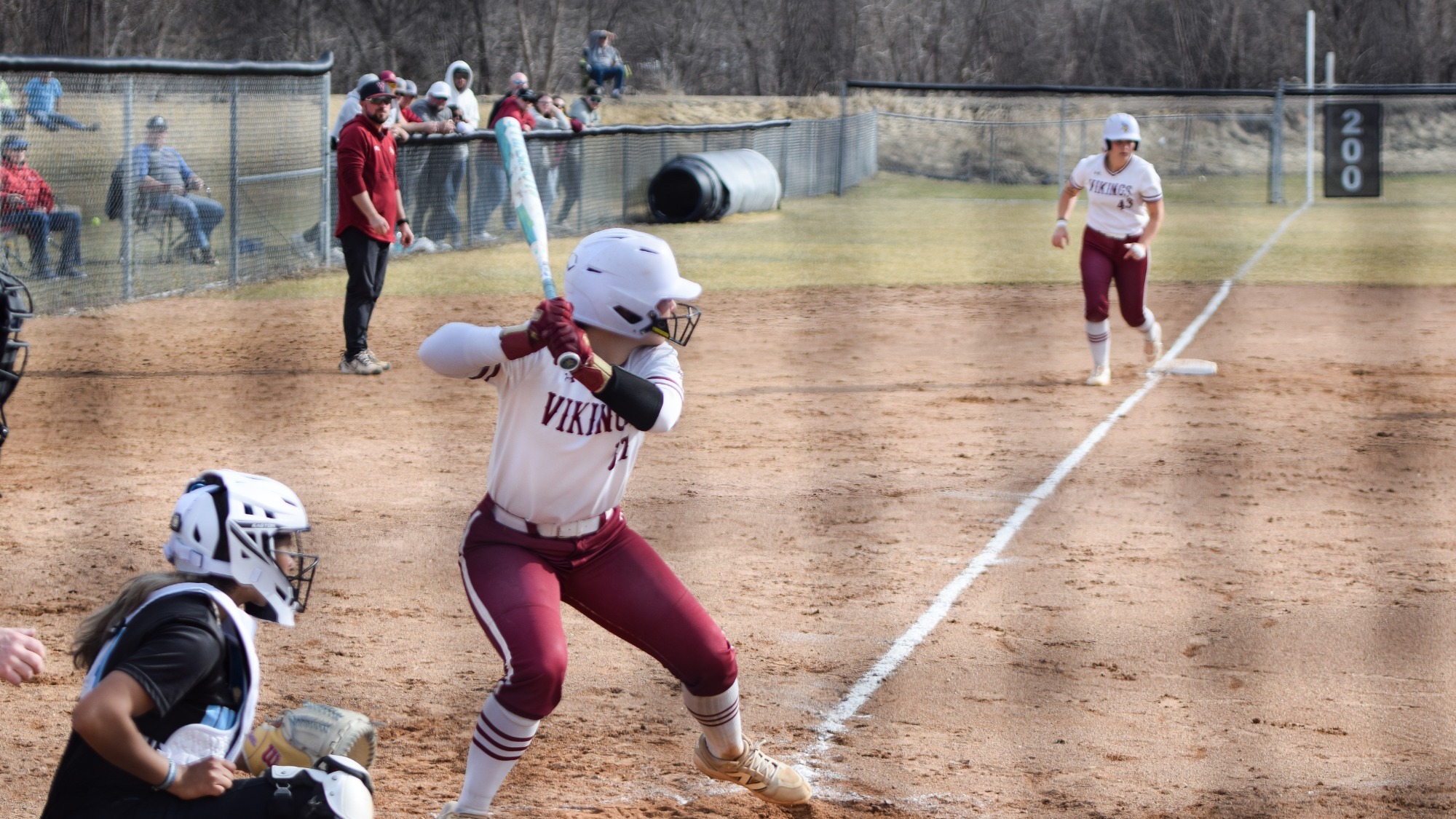 Viking softball player at bat with runner on third in the background.