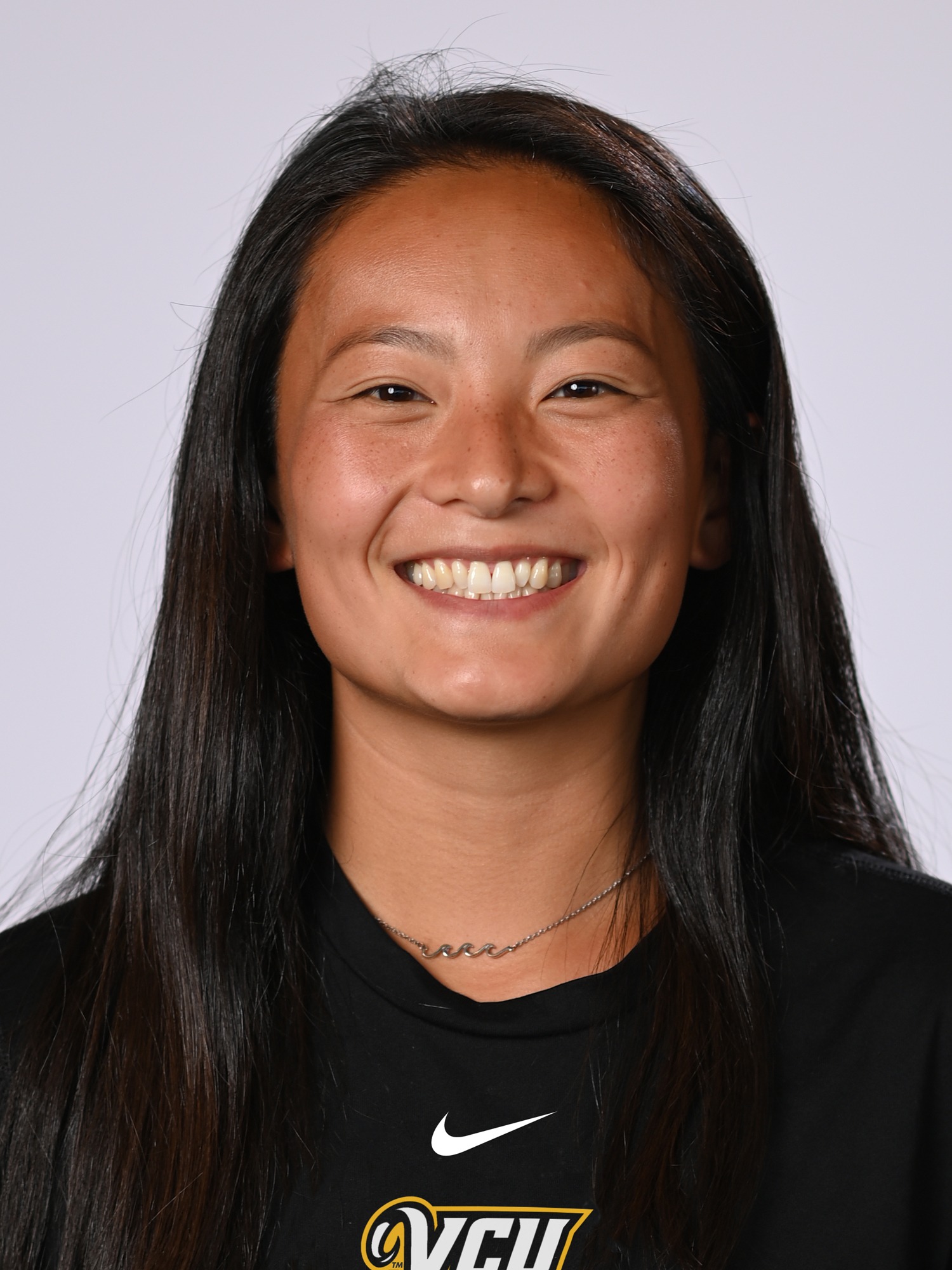 A posed headshot of Katherine Cotton smiling on a gray backdrop