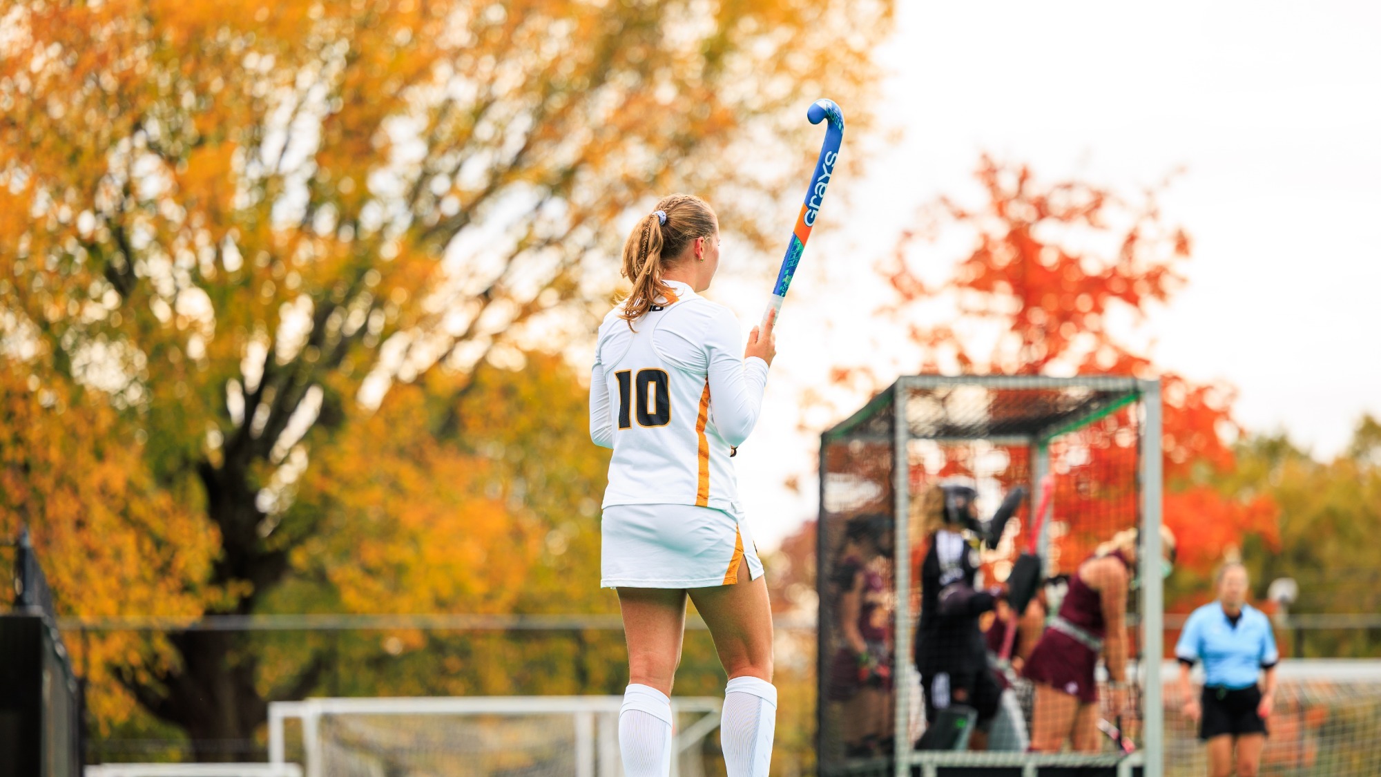 Lina Behrmann of VCU wearing a white 10 VCU jersey stands with her back to the camera lines up a penalty corner against Central Michigan