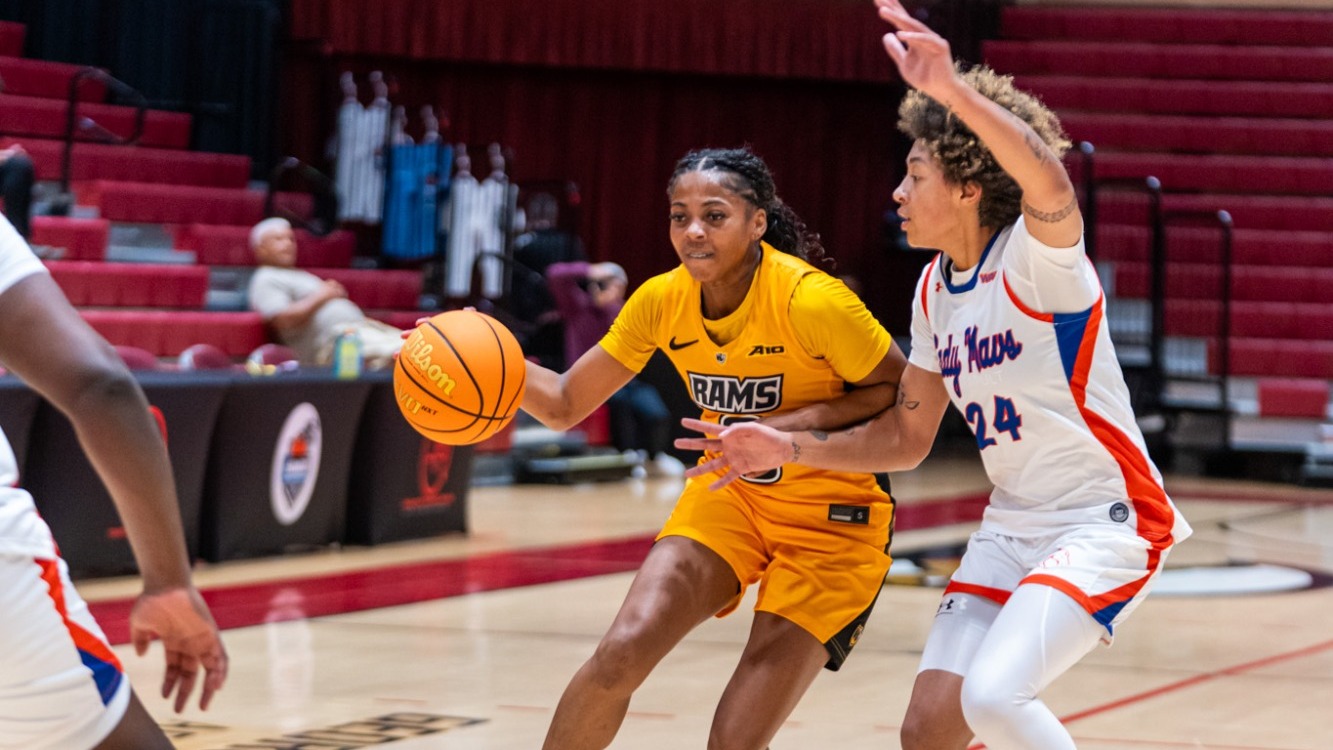 Ty Williams of VCU wearing a gold #0 jersey dribbles the ball while guarded by a UT Arlington defender at the North Shore Showcase