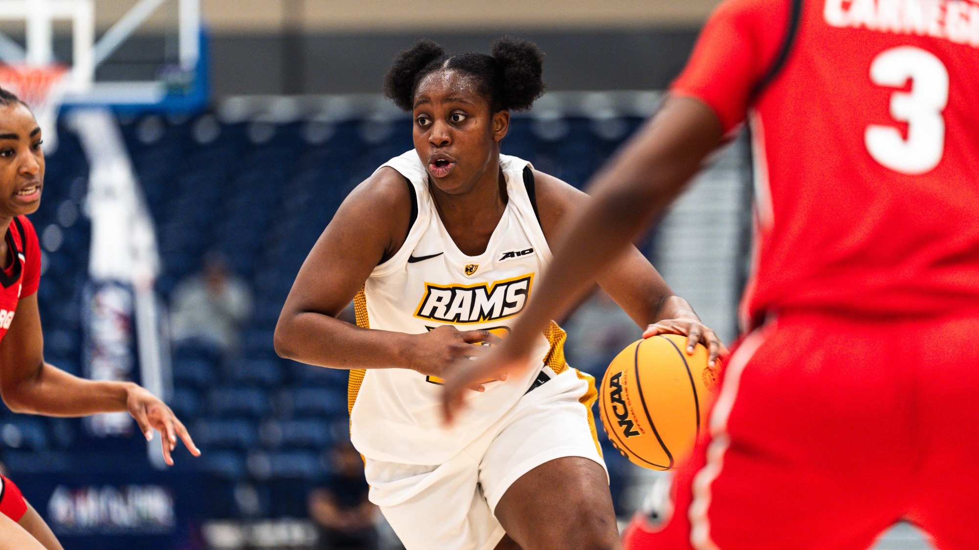 Patricia Augustin of VCU wearing a white #12 jersey dribbles the ball in a game against Georgia
