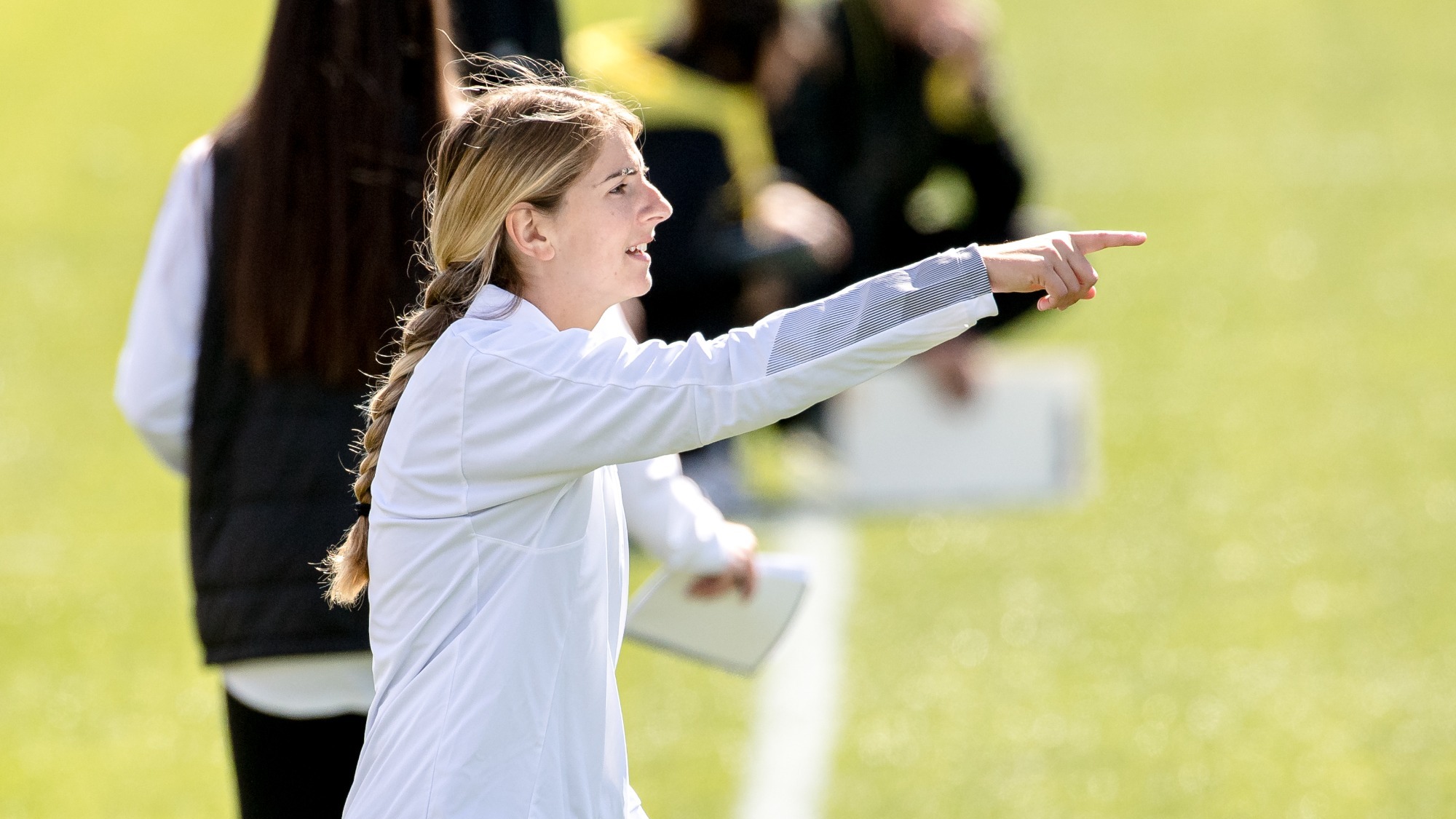 Bianca Tedesco holds out her arm and points while coaching a lacrosse game at Kennesaw State