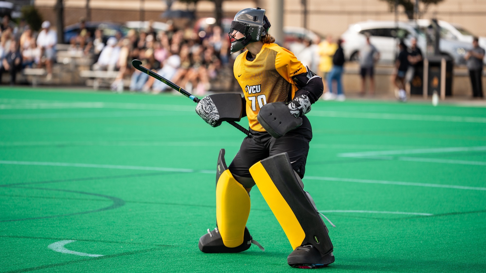 Emma Clements of VCU wearing a gold #70 stands in front of the goal during a field hockey game against Wake Forest