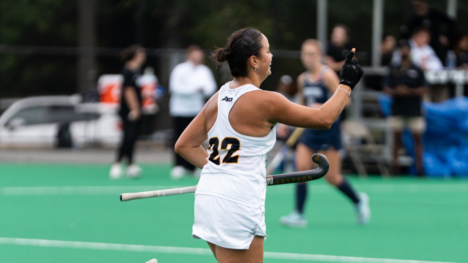 Ana Afonso of VCU wearing a #22 white jersey runs off the field with her finger pointed up and smiling during a game against Lock Haven