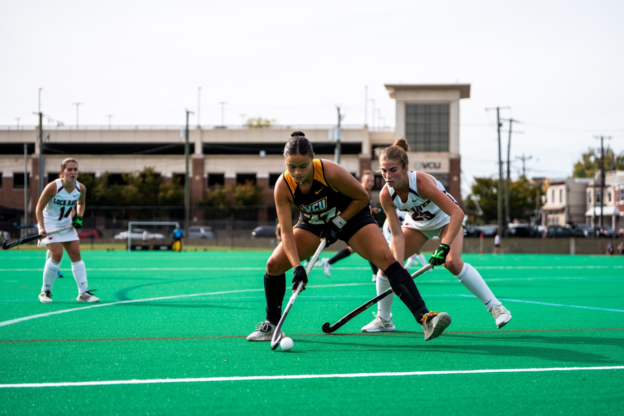 Ana Afonso of VCU wearing a black #22 jersey is guarded by a Lock Haven defender while dribbling the ball up against the end line